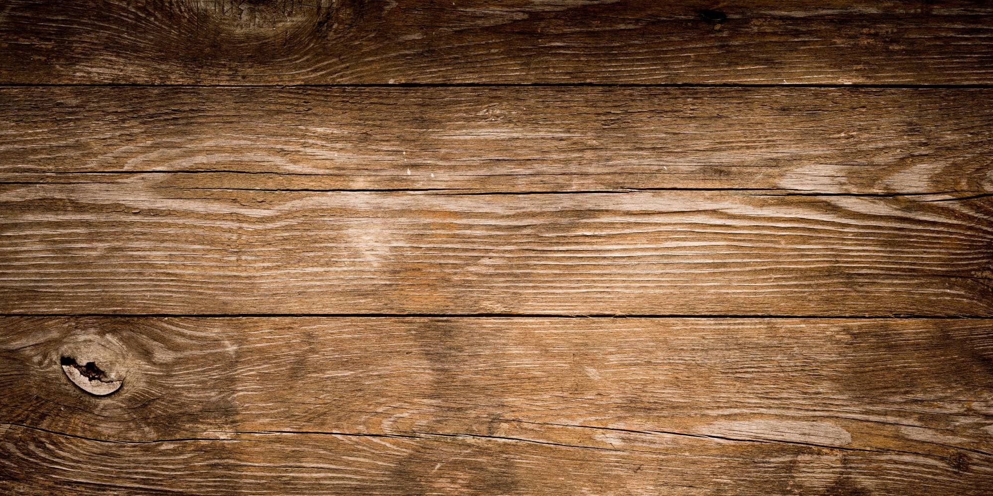Nahaufnahme von braunem, wettergegerbtem Holz mit sichtbar ausgeprägten Holzmaserungen und Knoten