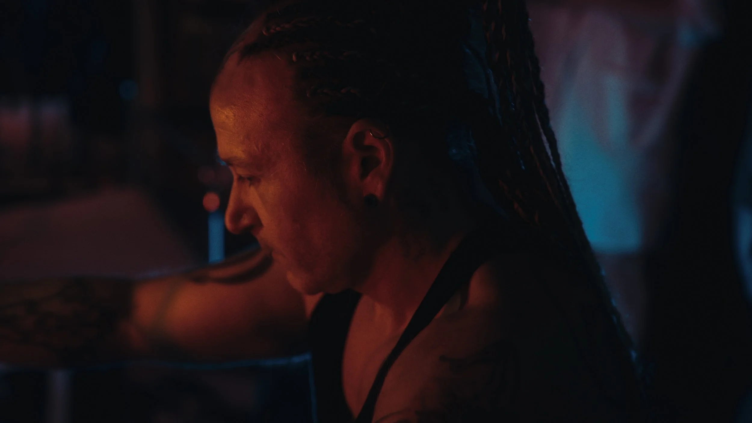 Profilo di una donna con dreadlocks che si esercita in una palestra con luci soffuse