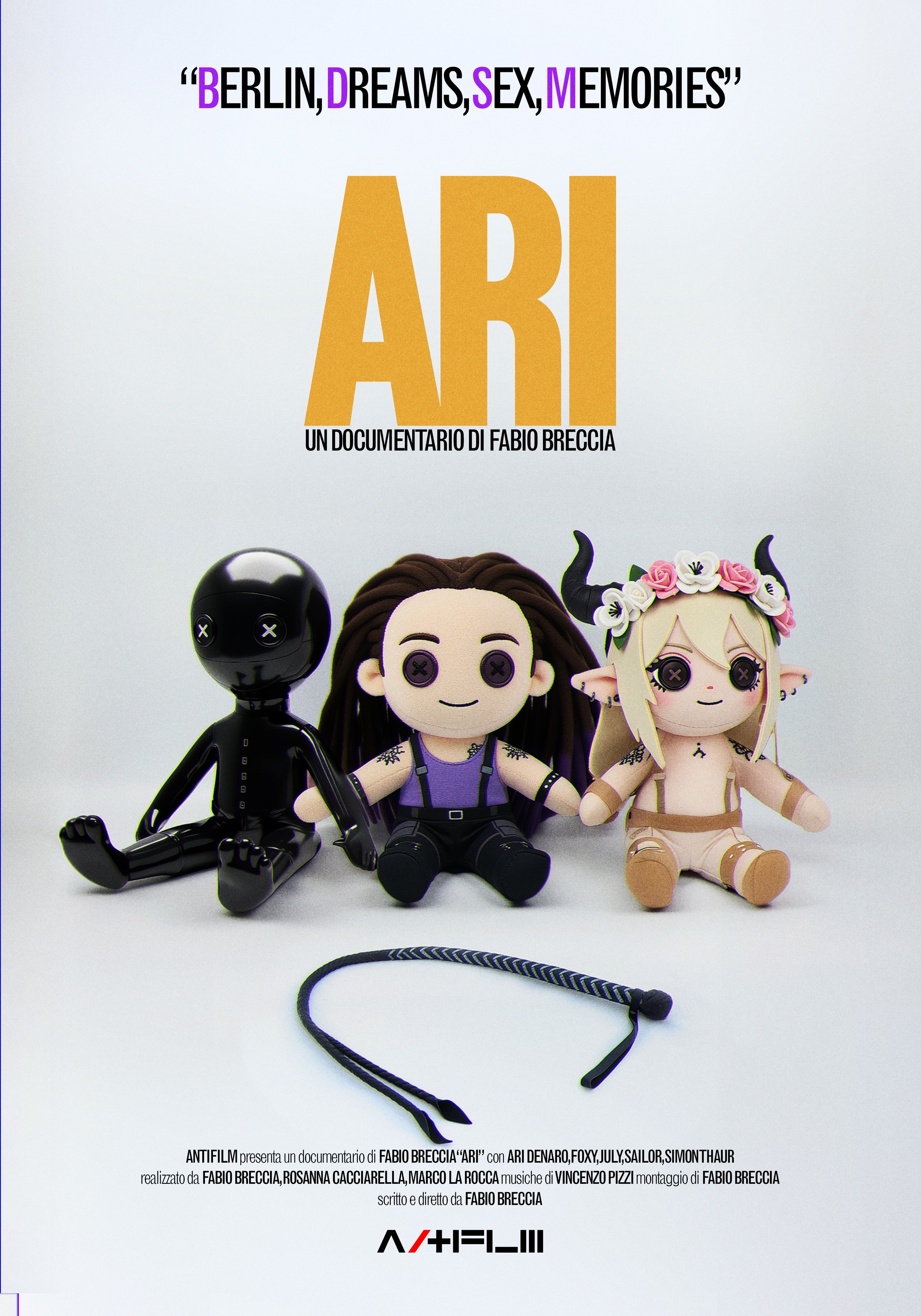 Locandina del documentario di Fabio Breccia intitolato "Ari" con tre bambole: una nera, una femmina con capelli ricci castani, e una creatura con corna, orecchie e abbigliamento fantasy, posizionate davanti a uno sfondo bianco.