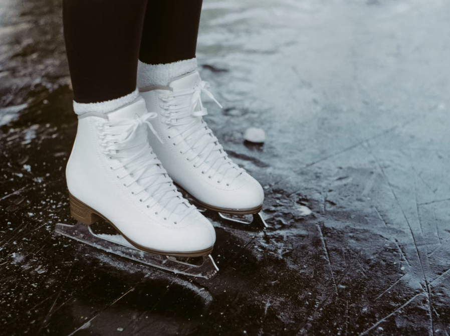 A photo of white fingers skates on black ice.