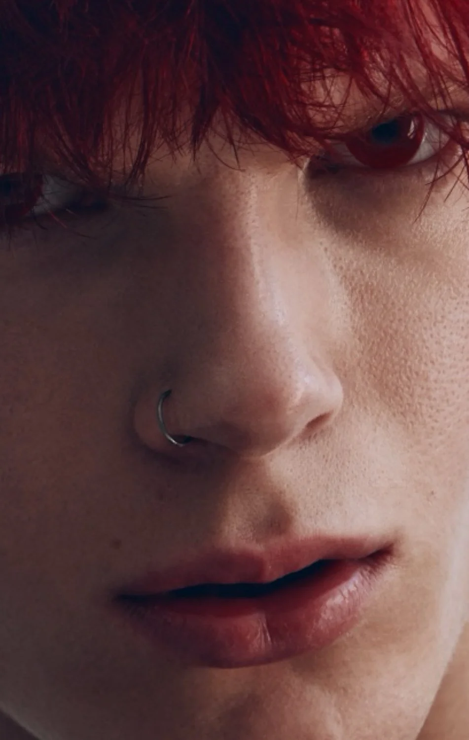 Close-up of a person's face with red hair, a nose piercing, and slightly parted lips.