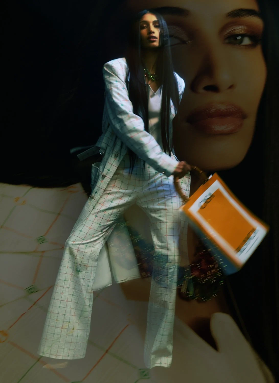 A woman in a white checkered suit holding a clipboard in front of a large poster of herself.