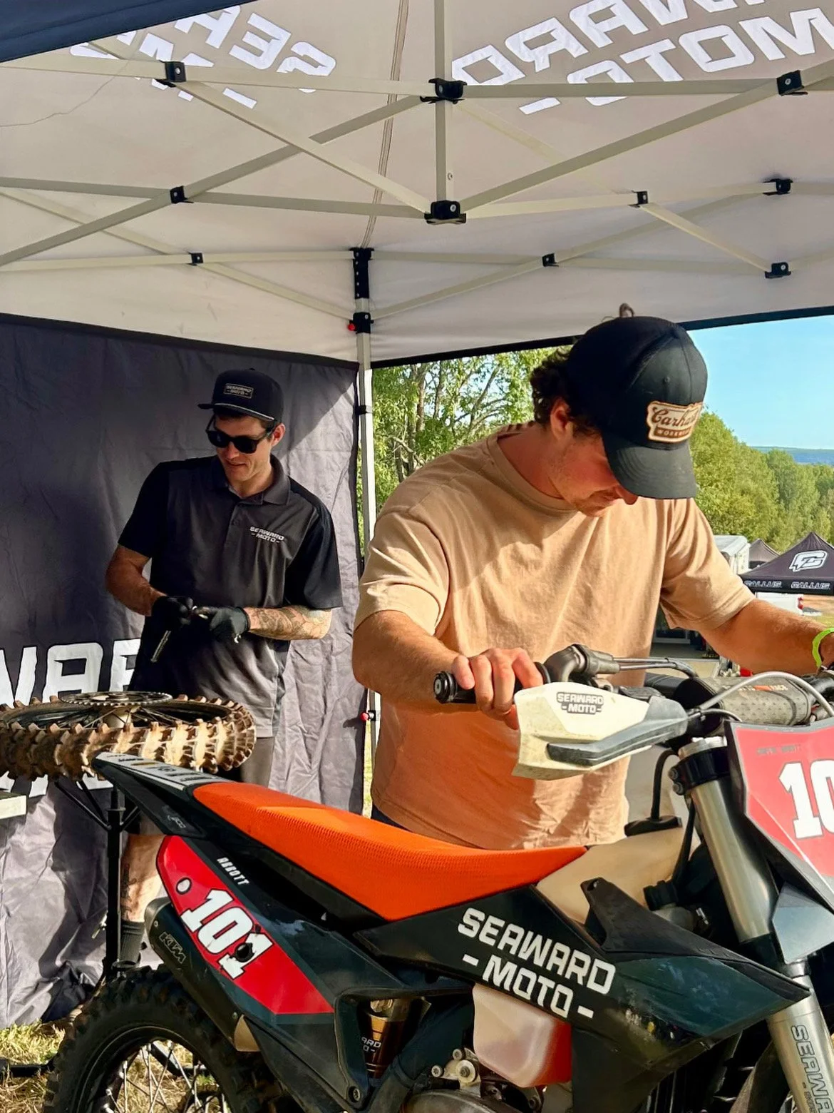 Jake Seaward with rider Griffin Abbott under pit tent at motocross event