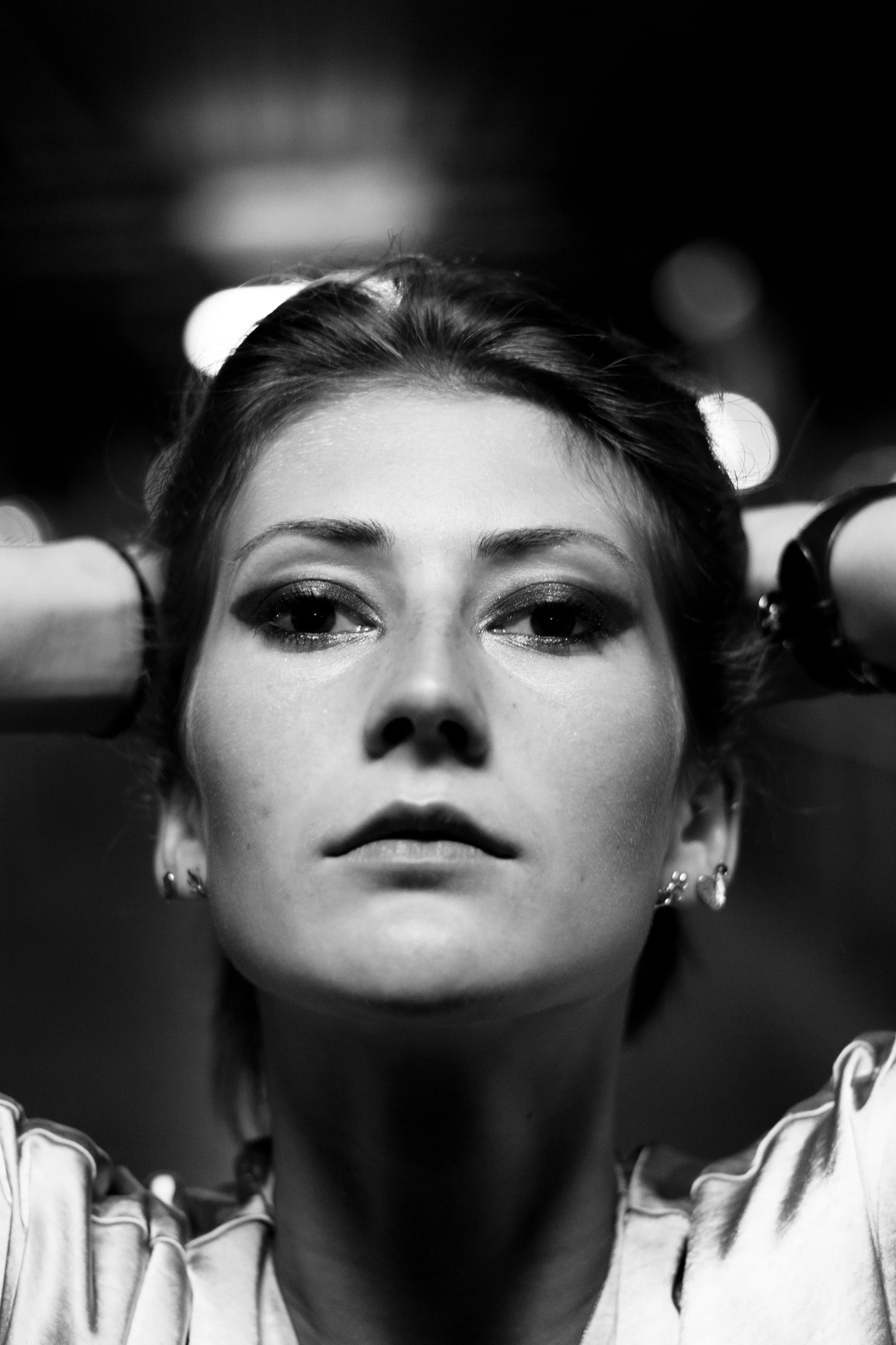 Une femme avec les bras levés derrière la tête, regardant direct dans l'objectif, en noir et blanc.