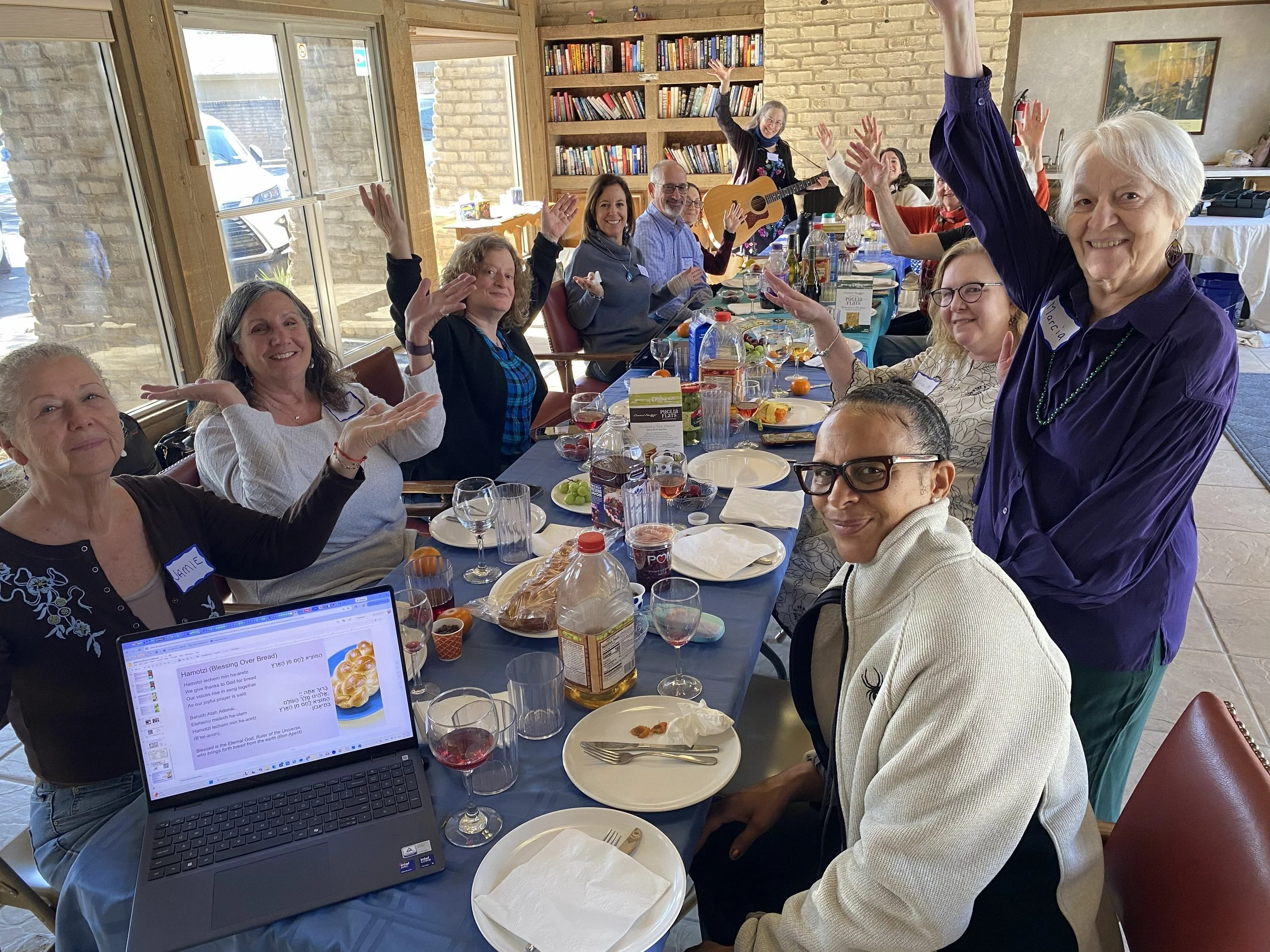 Participants smiling and raising hands like trees at a Kol Shira Tu Bishvat seder in Austin, February 2026.