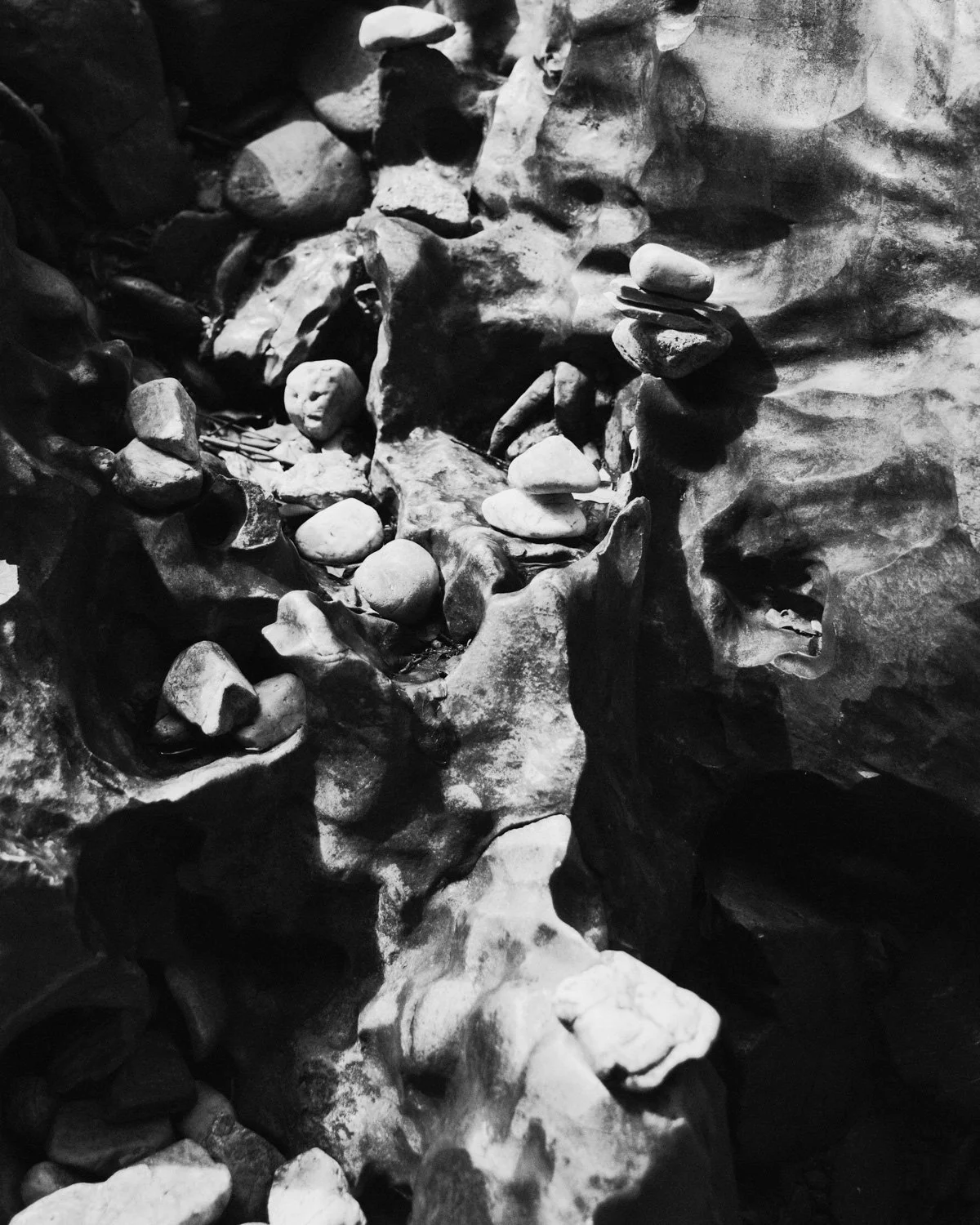 Rocce levigate e ciottoli in una parete rocciosa, alcune in equilibrio su altre.