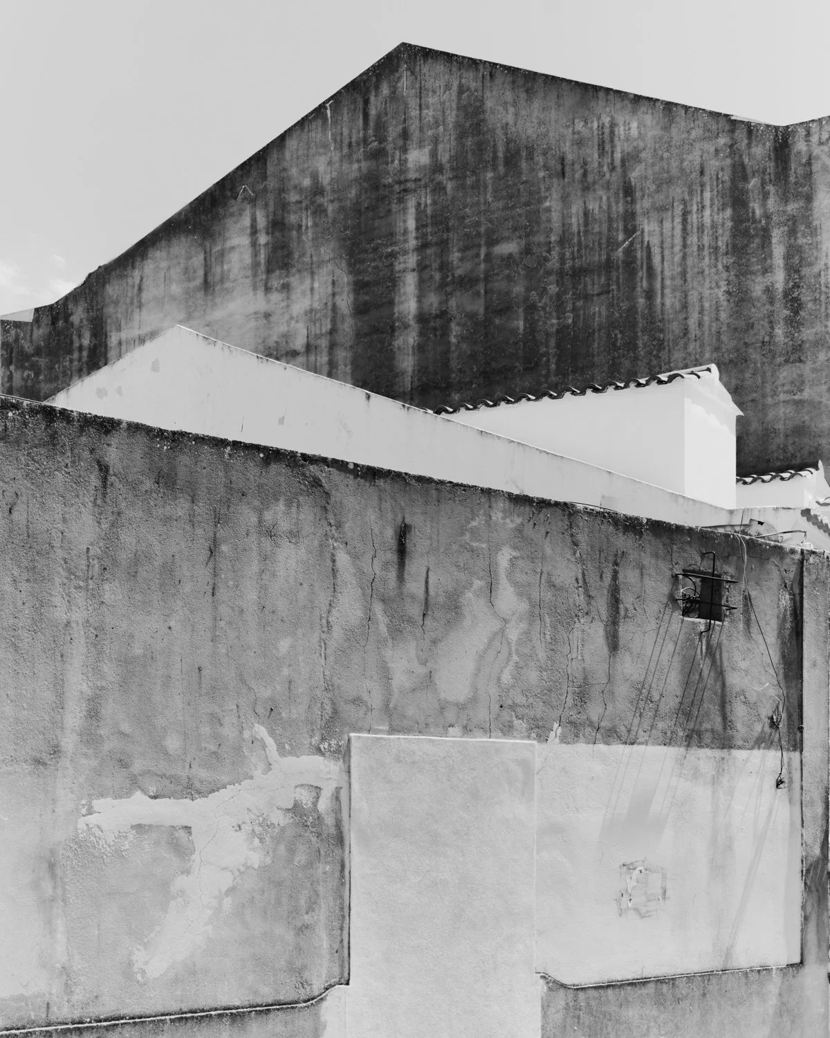 Veduta di muri di edifici in bianco e nero con superfici vissute e linee di cavi elettrici.