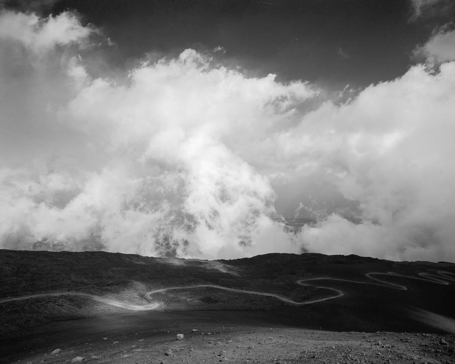 Paesaggio montano con strada tortuosa e nuvole minacciose nel cielo