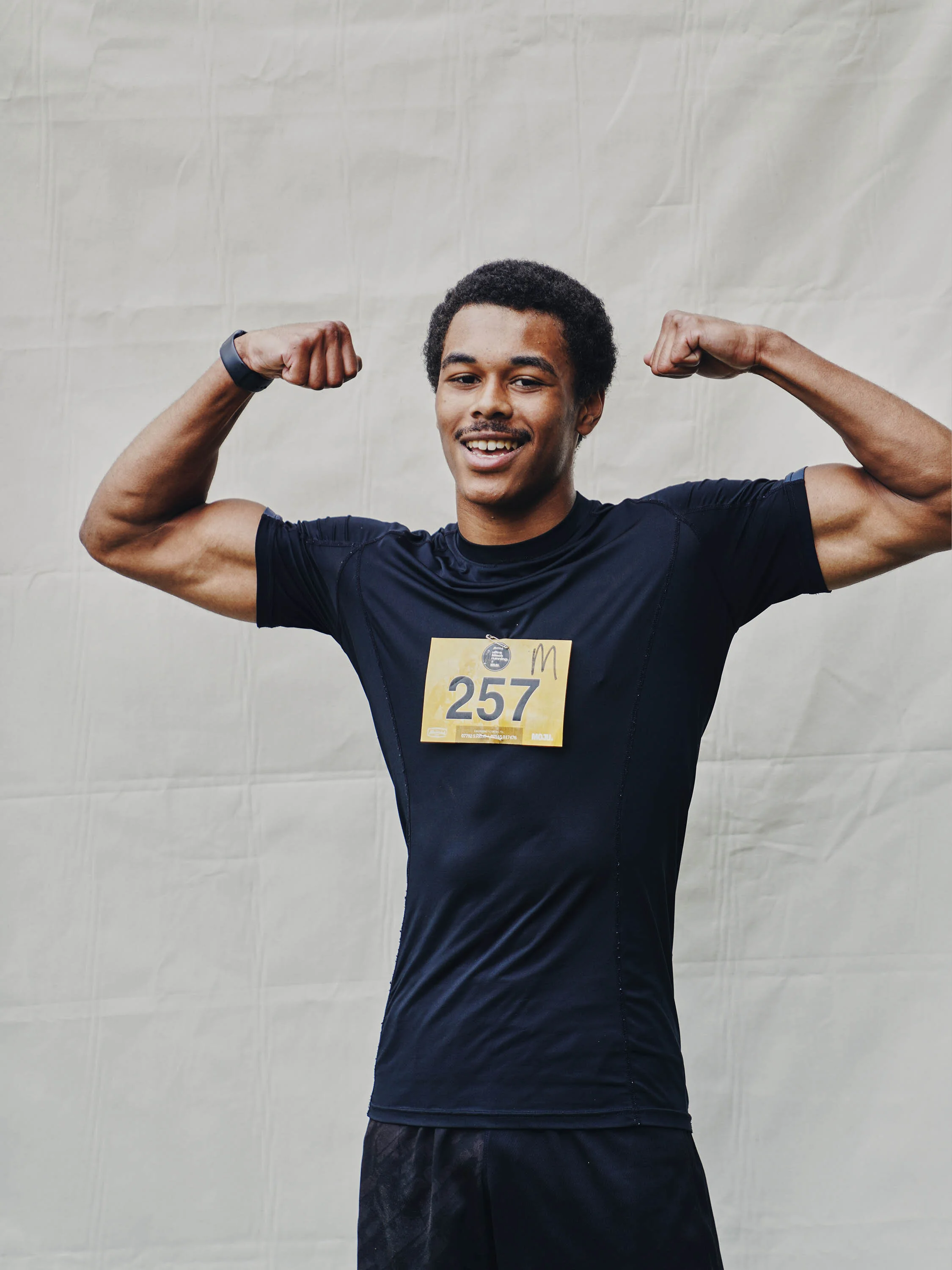 Young man in running clothes showing his biceps at a race event