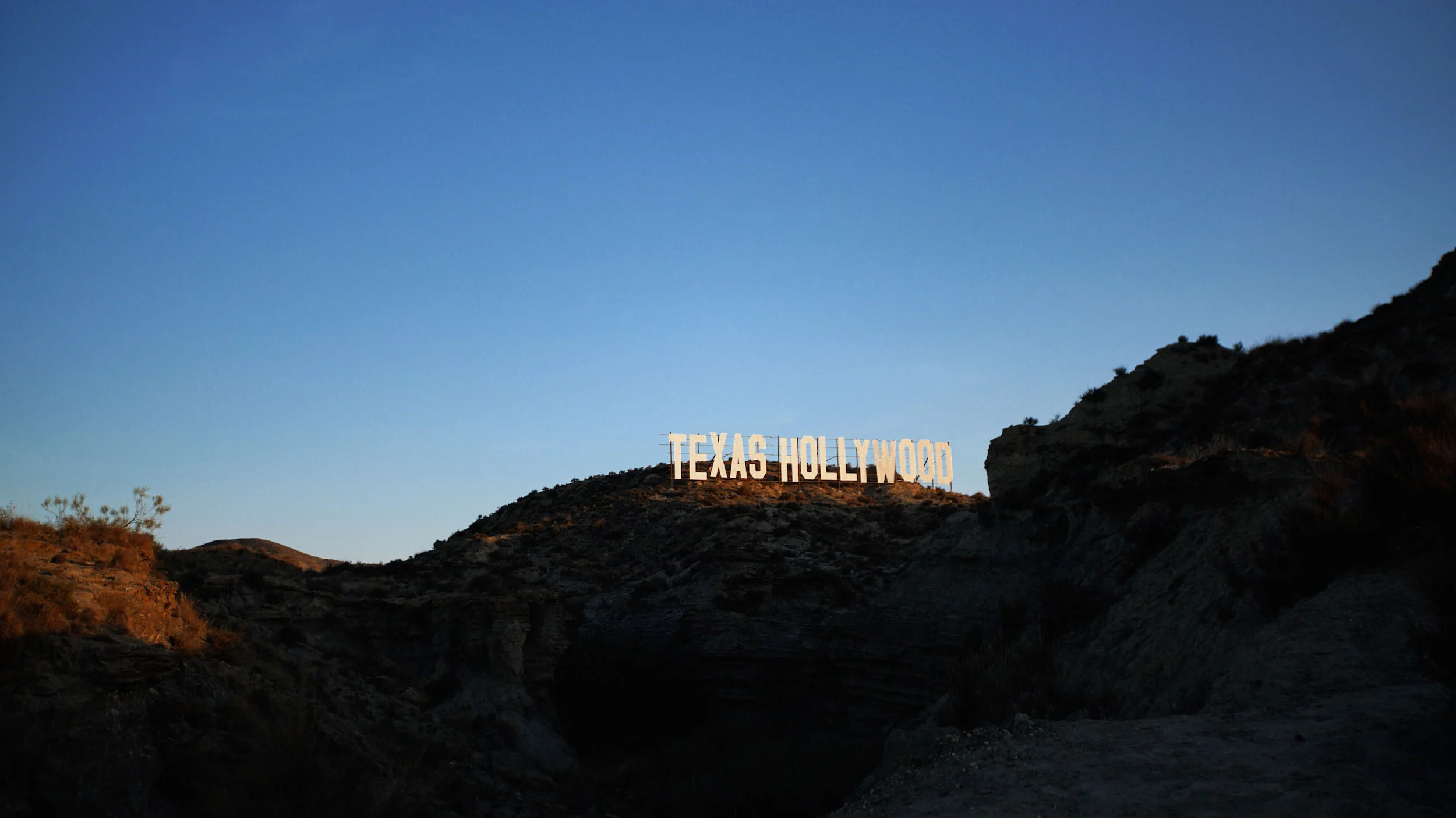 View of the Hollywood sign on a hillside in Texas during sunset.