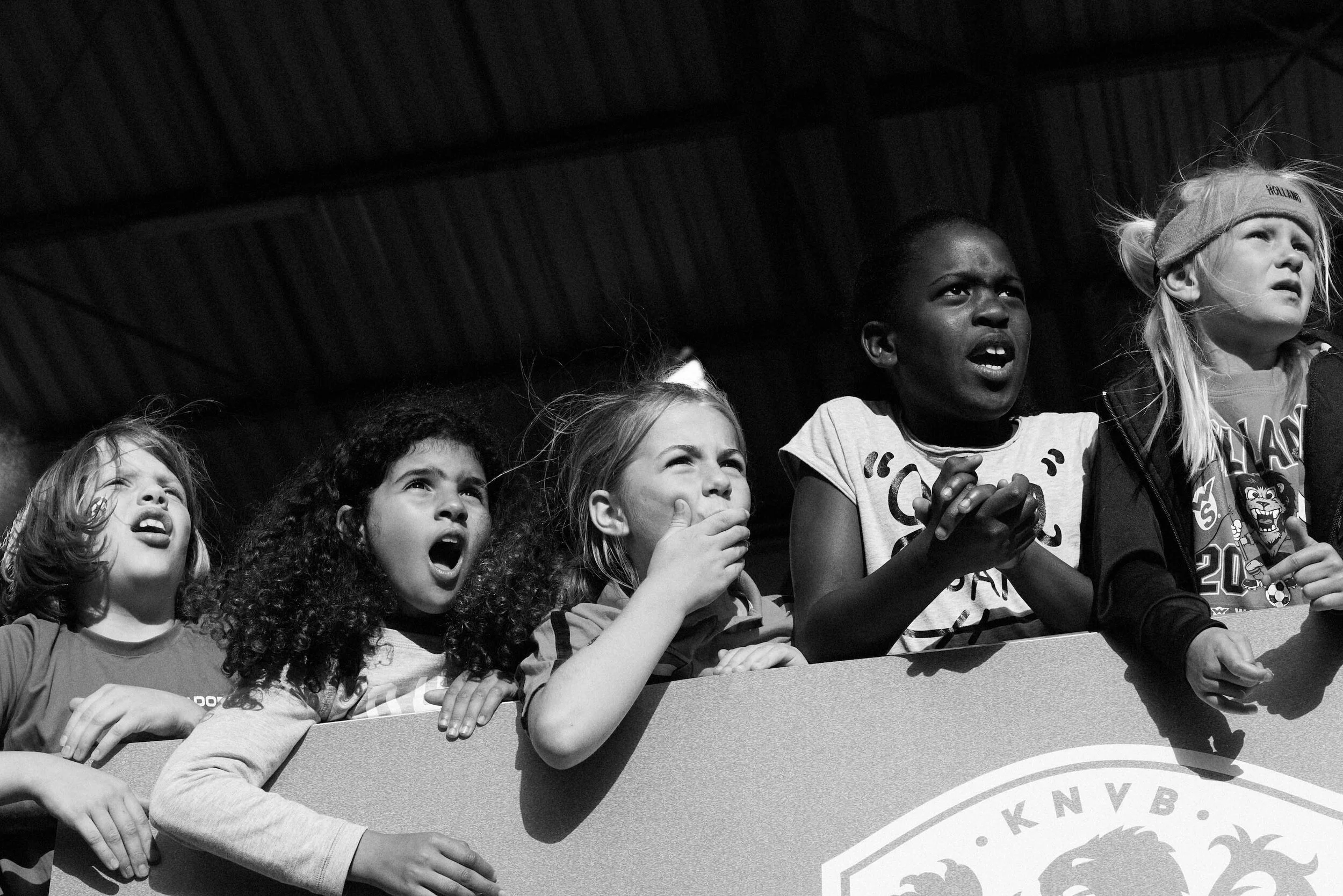 Group of young girls watching an event with intense expressions in black and white.