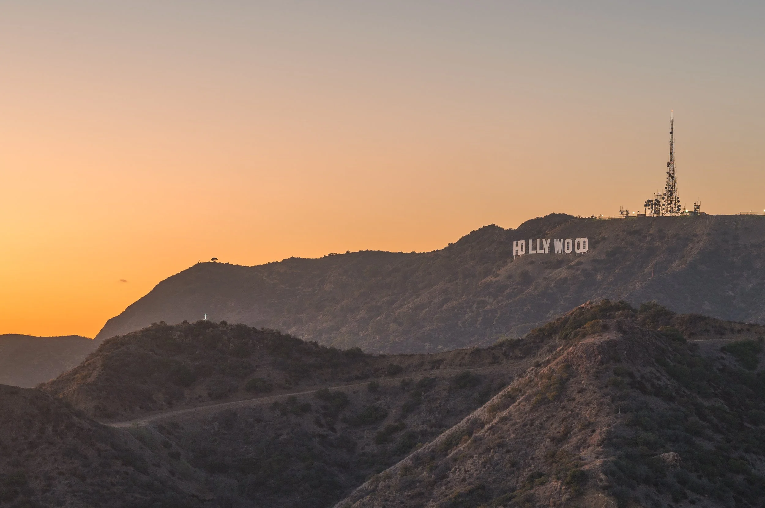 Sunset over the Hollywood Hills with the iconic Hollywood sign and radio towers on the hillside.