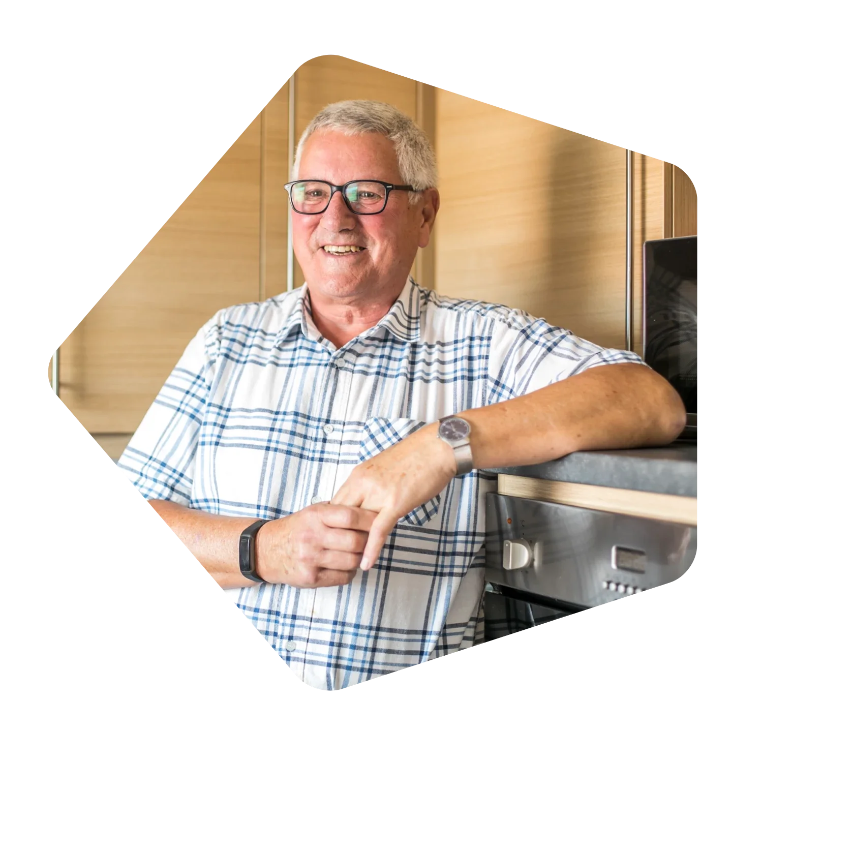 Older_man_leaning_against_kitchen_top_and_smiling.webp