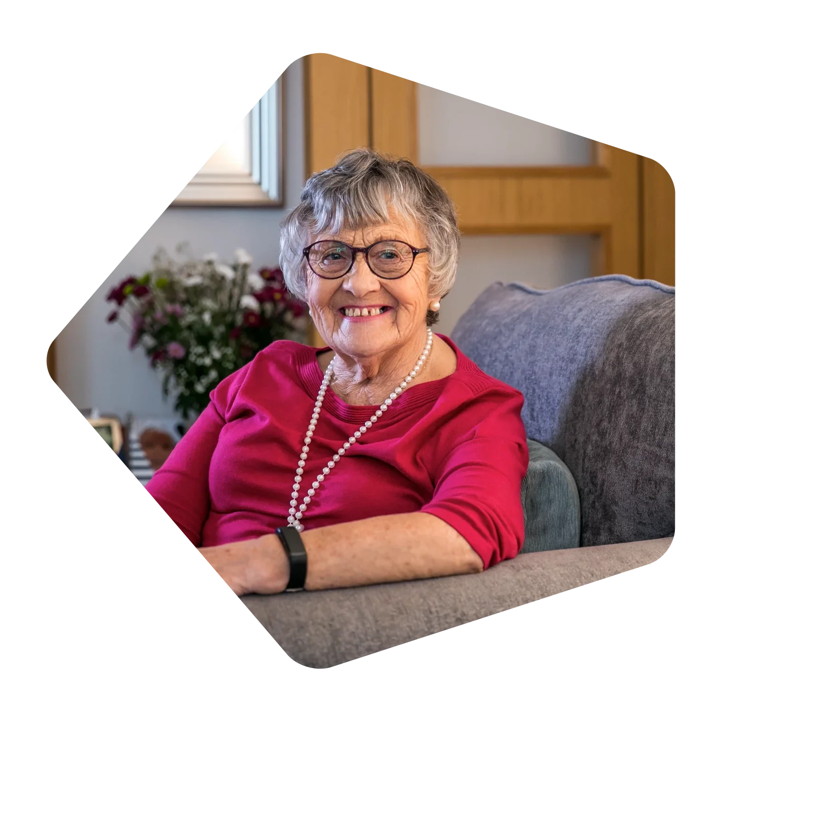 Older_woman_in_red_top_smiling_in_armchair.webp
