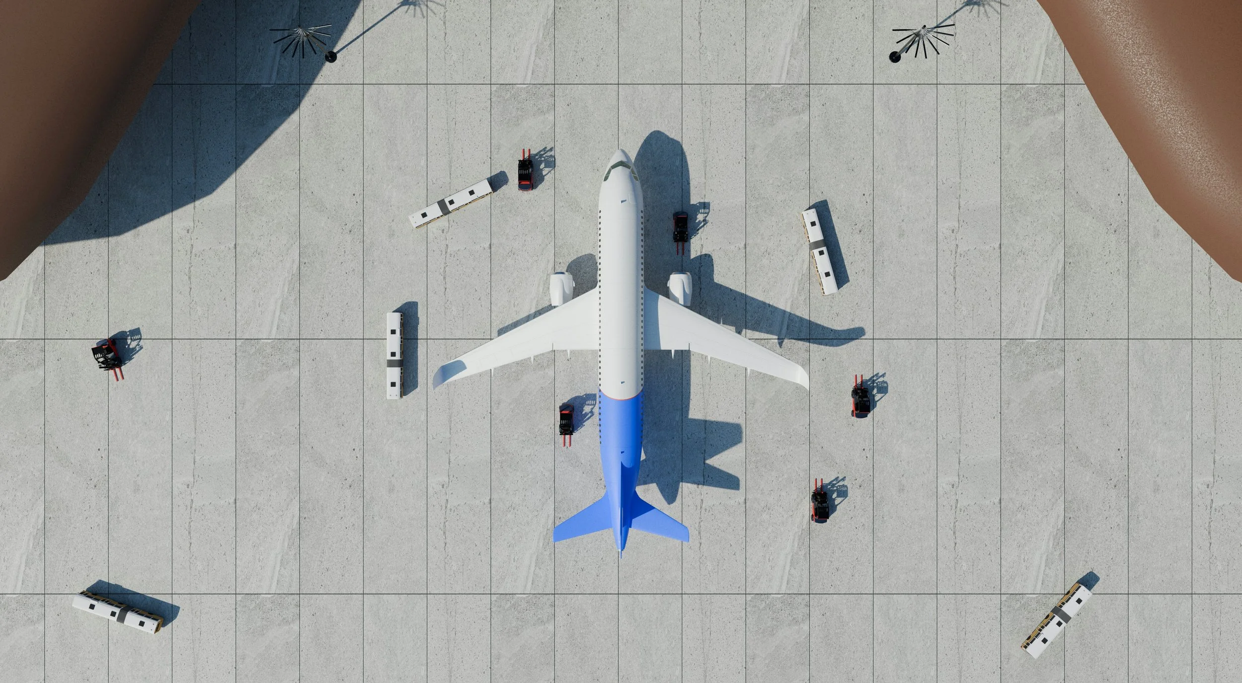 Top view of an airplane parked at a gate on a tarmac, surrounded by luggage carts and ground service vehicles.
