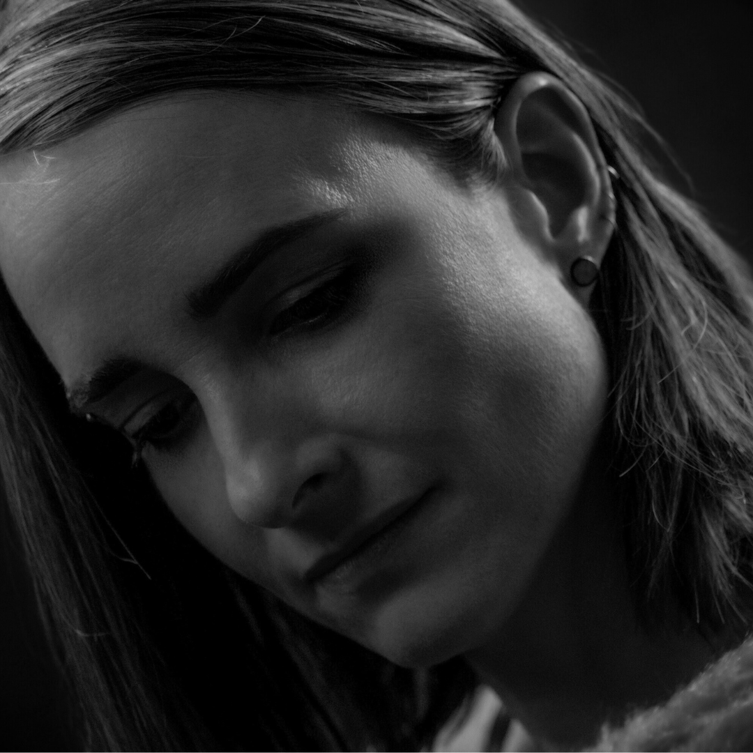 Close-up of a woman with short hair, showing her face in black and white, with a calm expression.