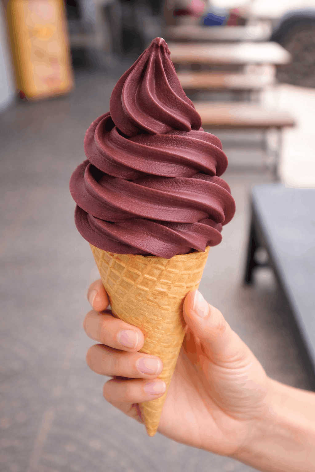 Nieve de chocolate morado en conos de waffle, sostenida por una mano.
