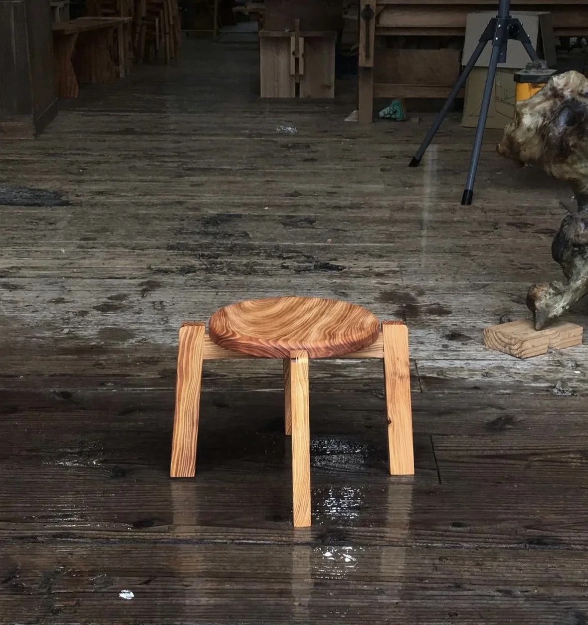 Kleiner runder Holzstuhl auf einem holzfußboden in einem Raum.