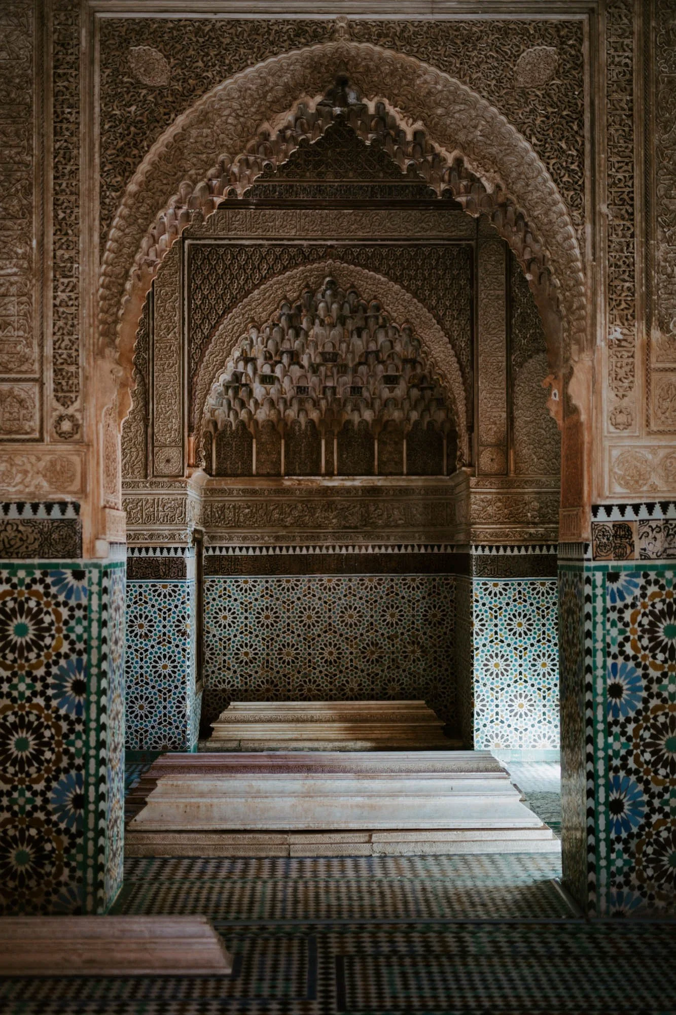 Intricate Moroccan-style interior with ornate carvings, colorful tilework, and arched niches.