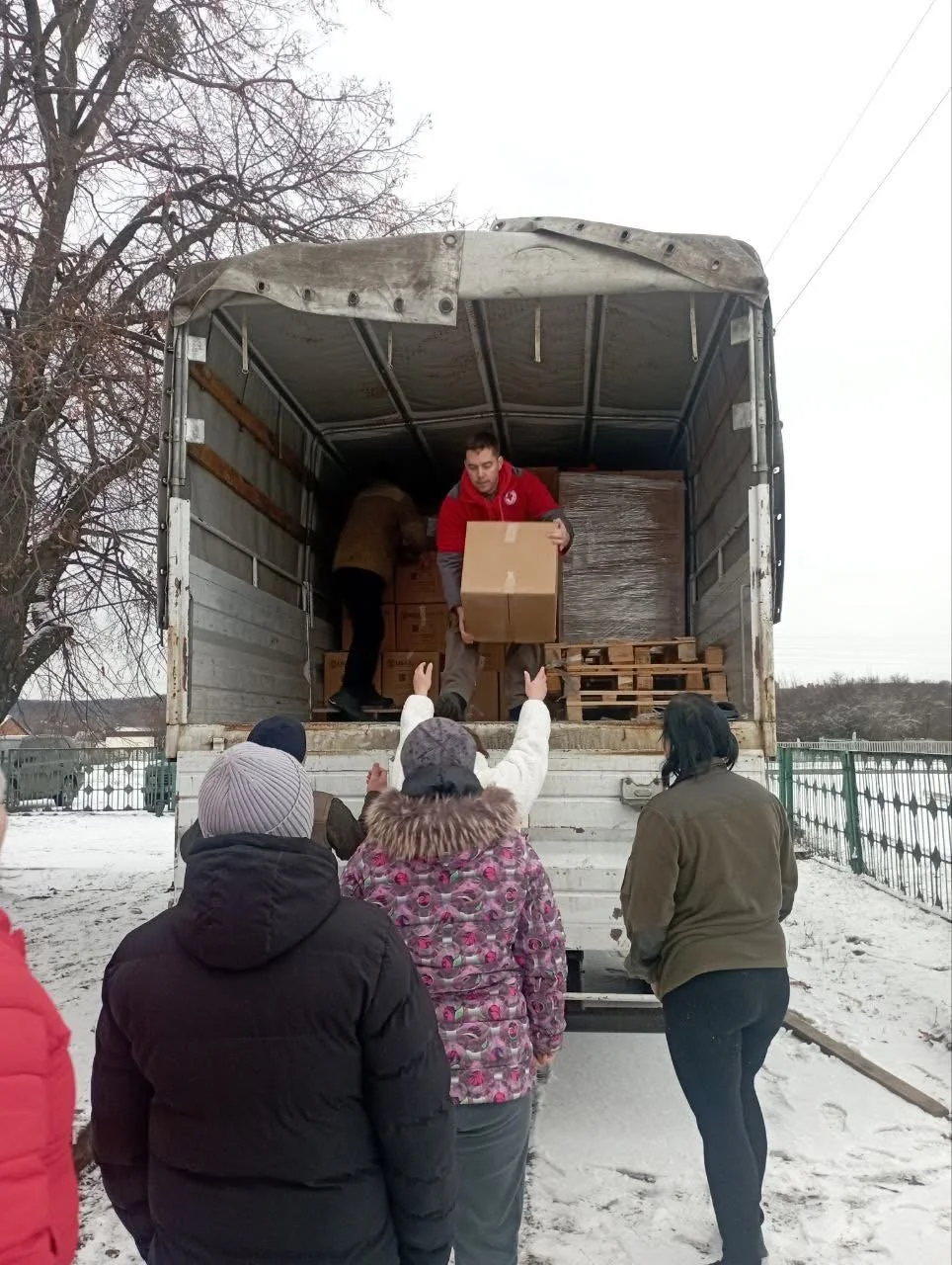 People receiving boxes from a moving truck outdoors in winter.