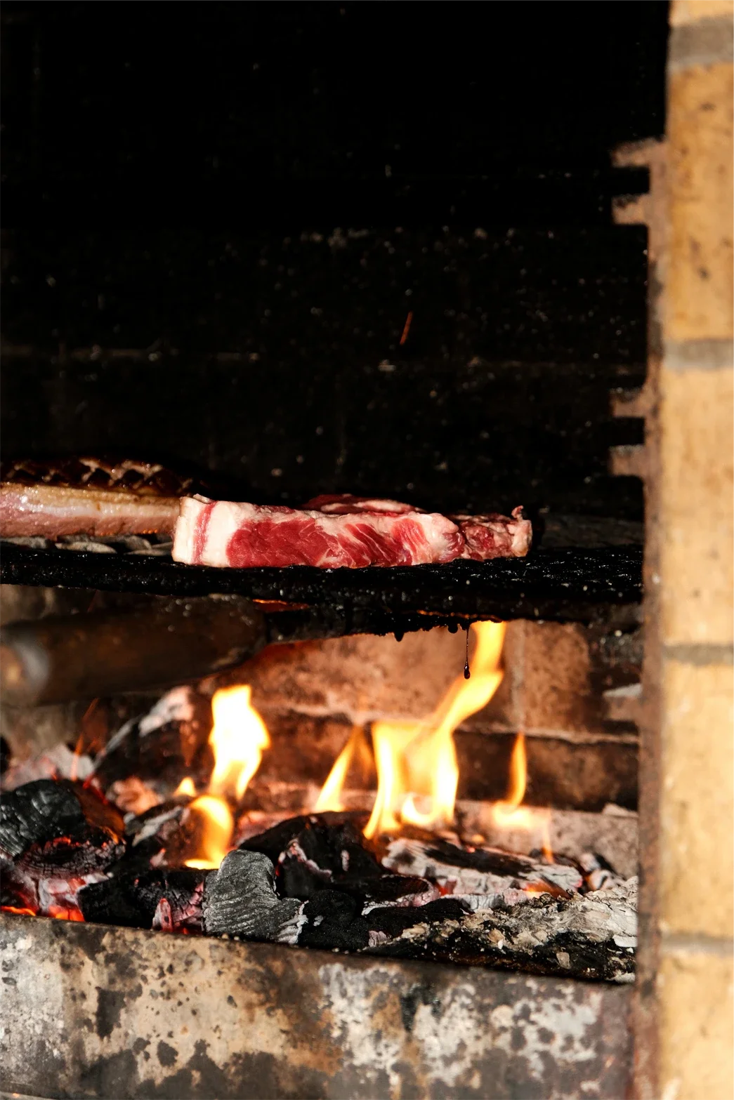 Une pièce de viande en train de cuire sur un grill à charbon ardent.