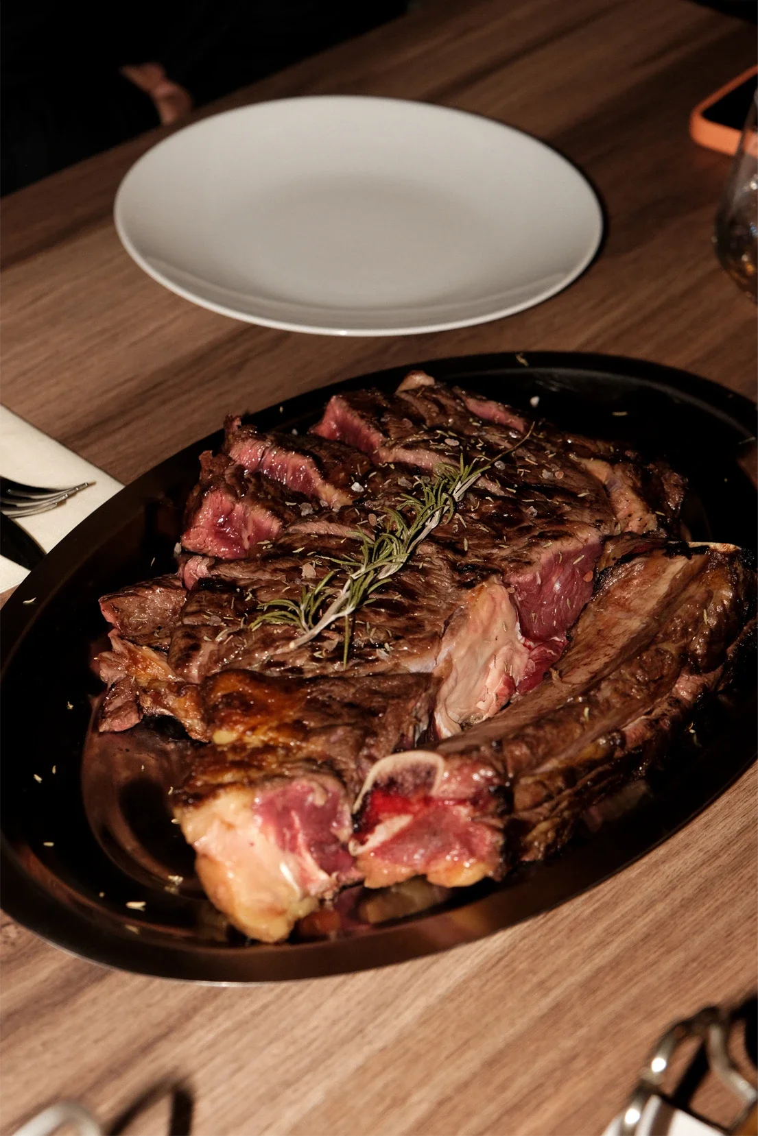 Steak de bœuf grillé avec des herbes sur un plat en cuisson.