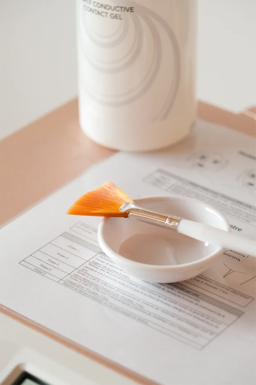 Une bouteille de gel de contact, un pinceau et une fiche d'instructions papiers sur une table.