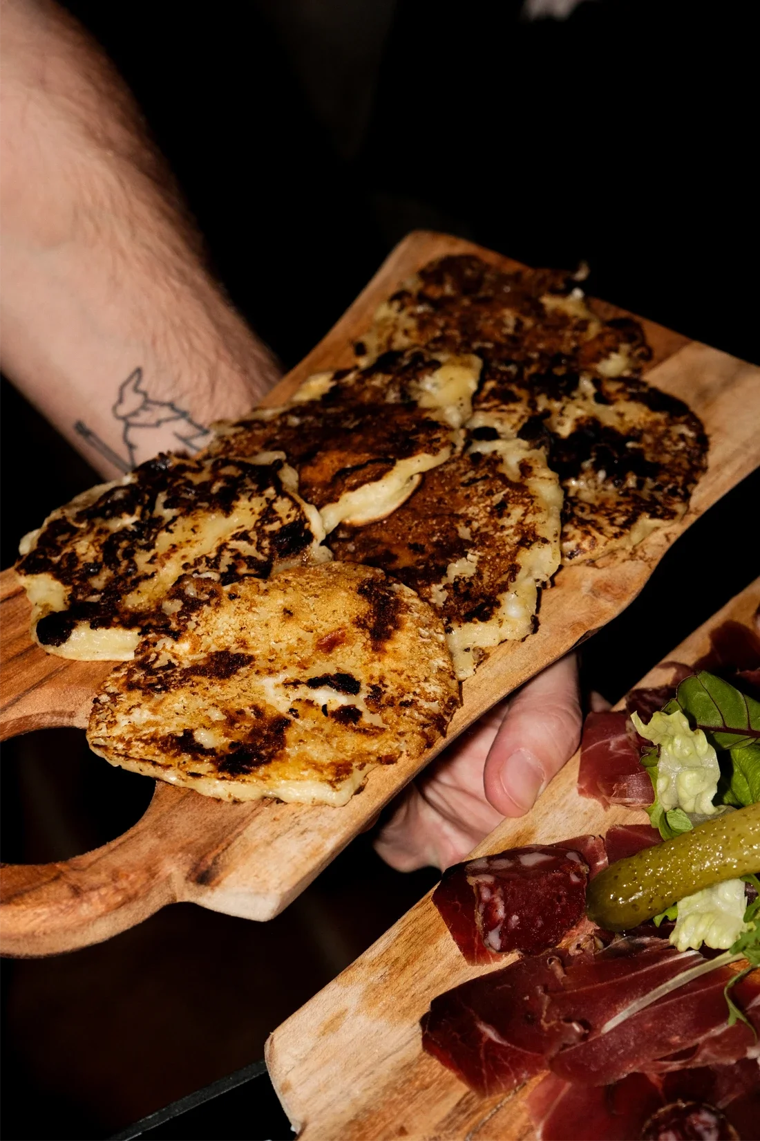 Garnitures de viande enroulée avec du rucola et un cornichon sur une planche en bois.