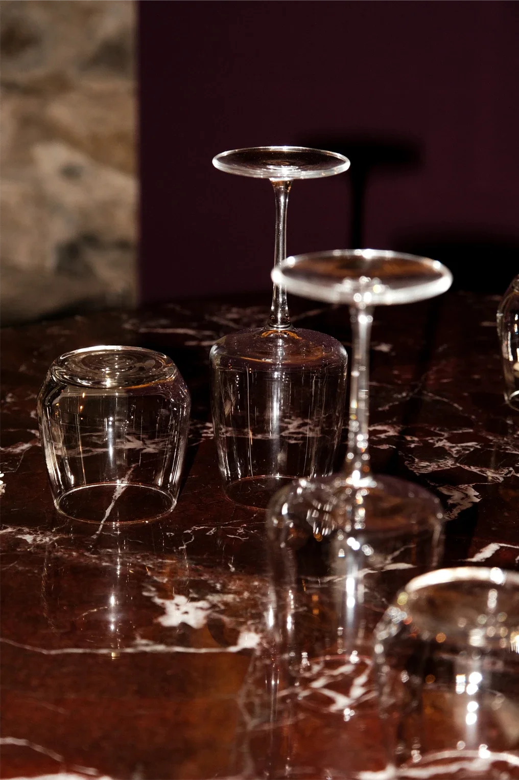 Verres à vin à l'envers et à l'endroit sur une surface en marbre sombre.