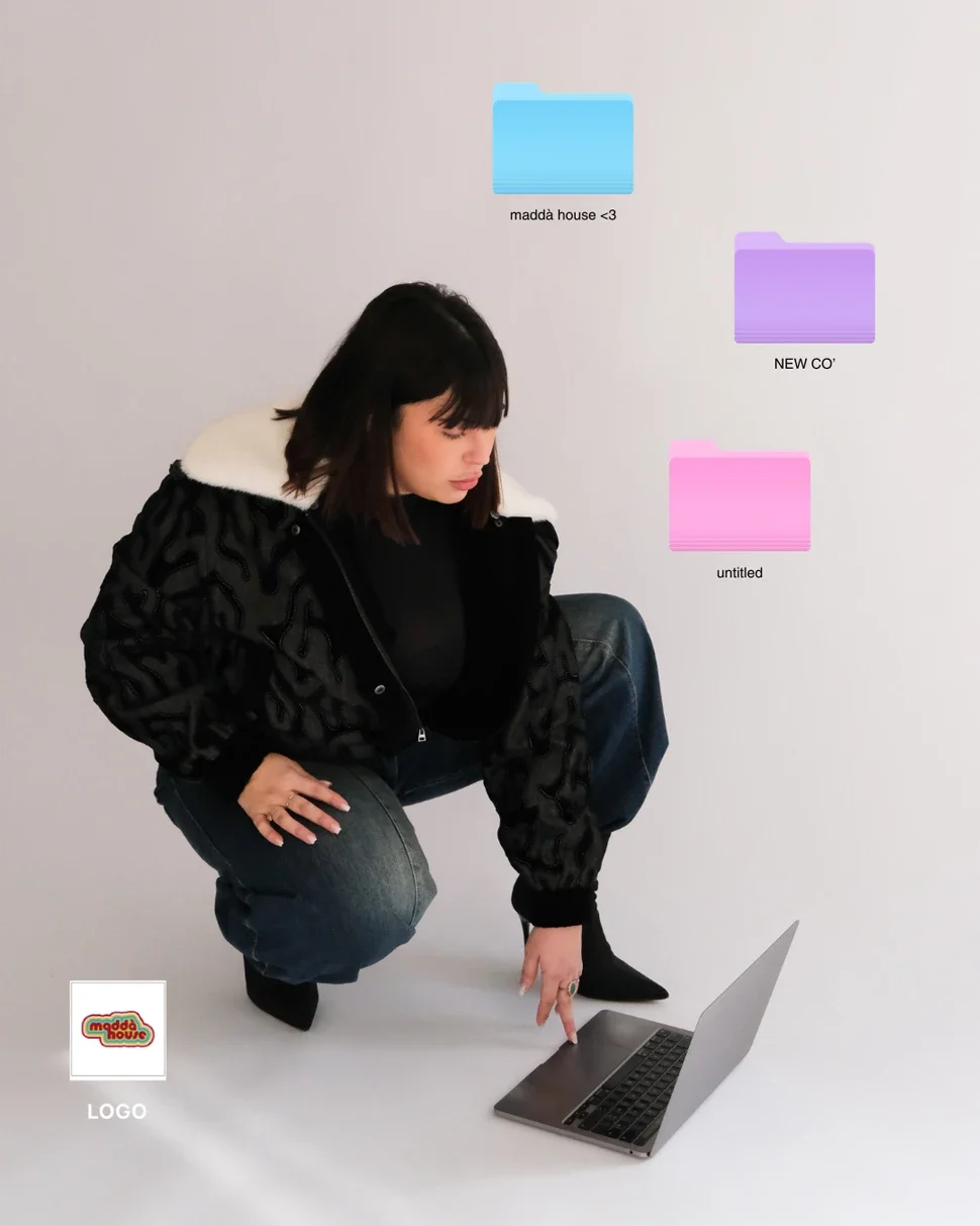 Une femme en jeans et veste noir plie un genou et pointe du doigt un ordinateur portable sur un sol blanc, avec des dossiers colorés et un logo en bas à gauche.