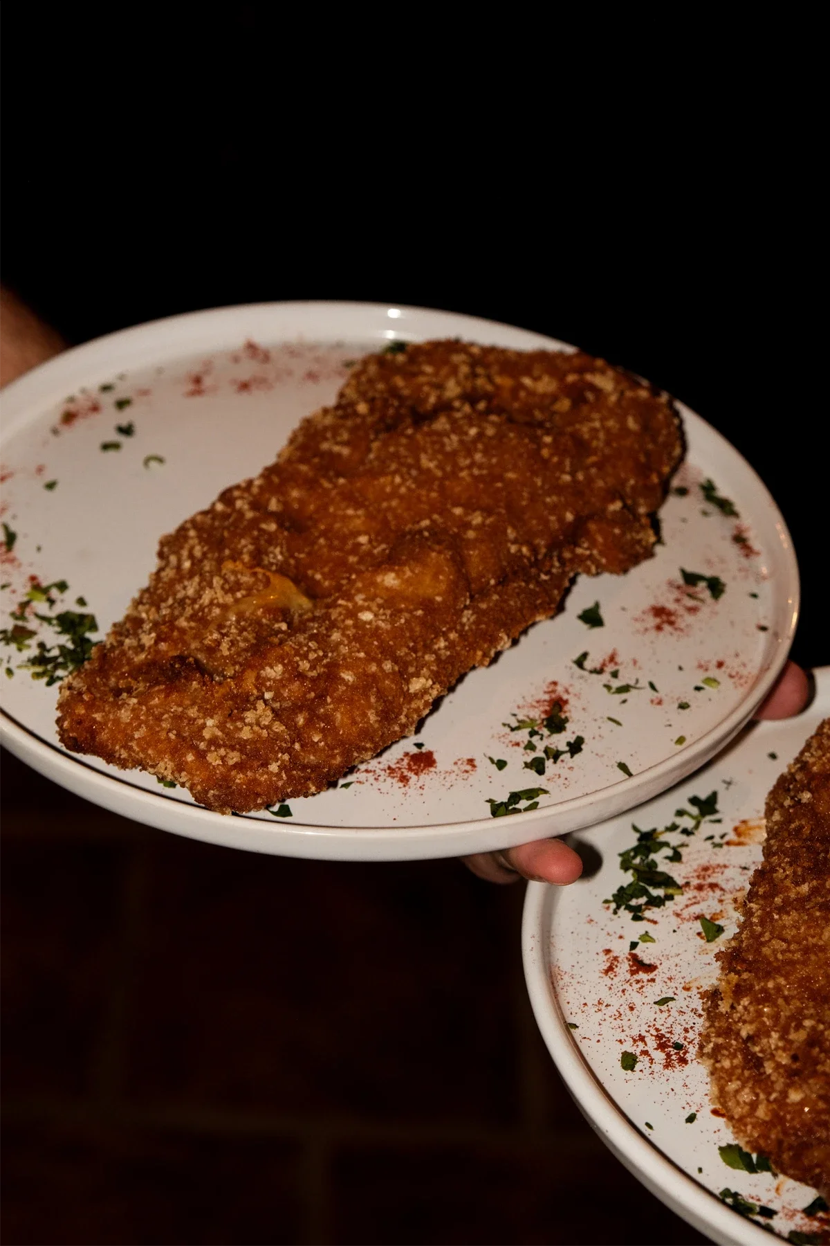 Assiette de poisson pané croustillant, servi avec des épices et des herbes sur une assiette blanche.