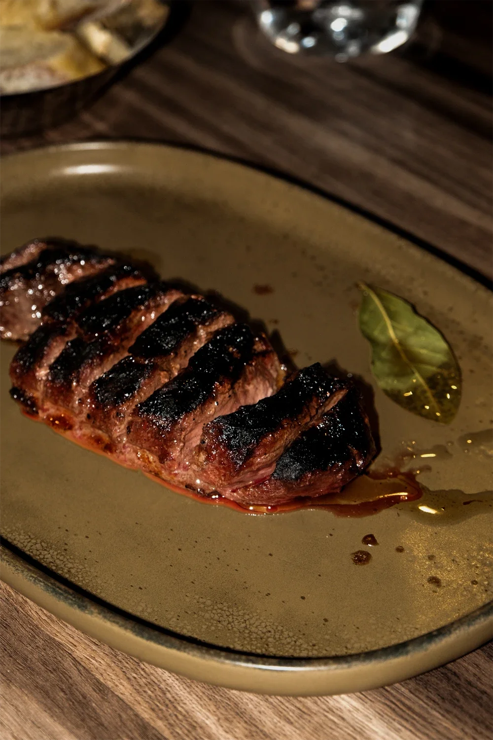 Un steak grillé avec des marques de cuisson, servi avec une feuille de laurier sur une assiette