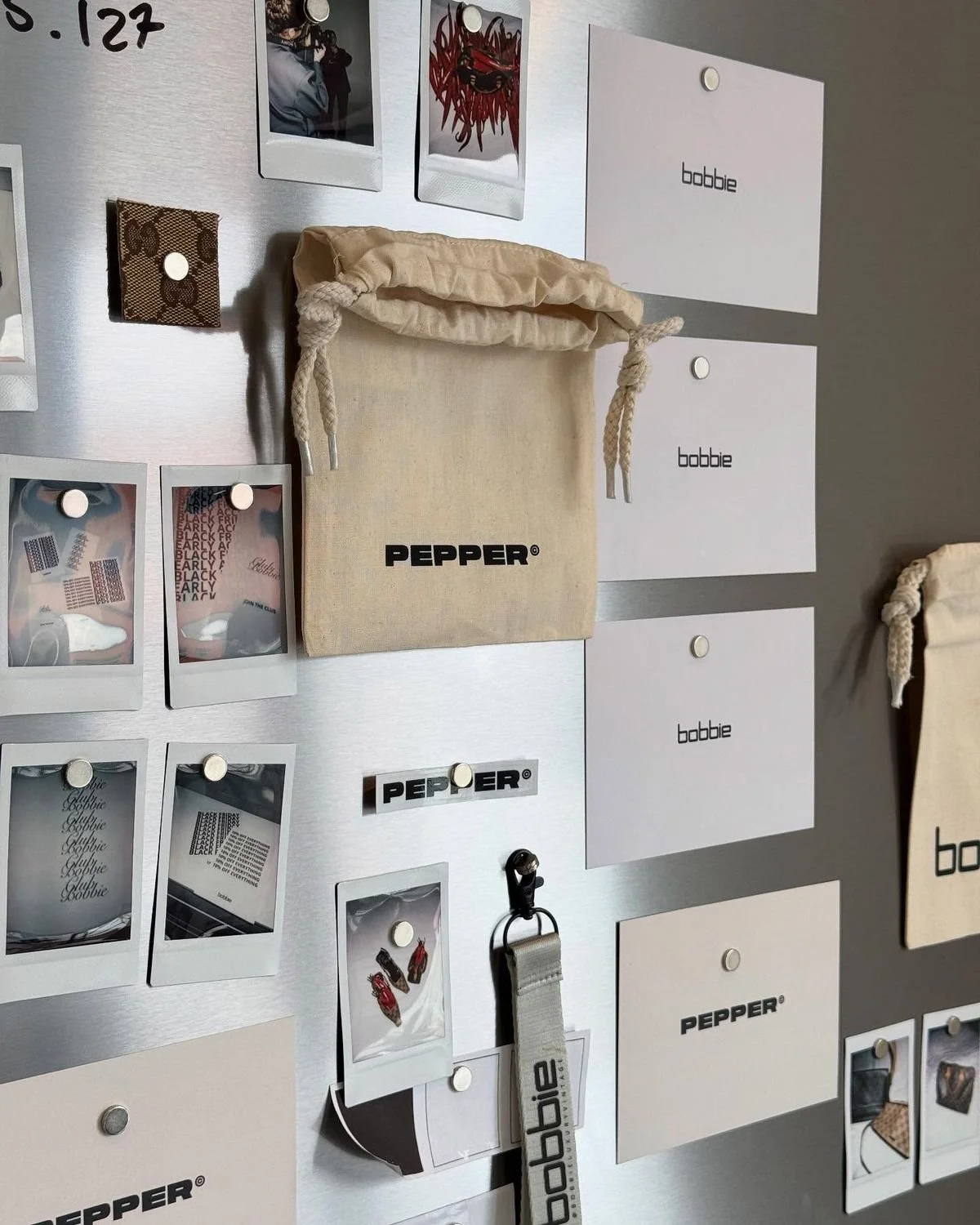 Mur d'organisation avec pochettes, stickers, bijoux et une pochette en tissu beige marquée du mot «PEPPER».