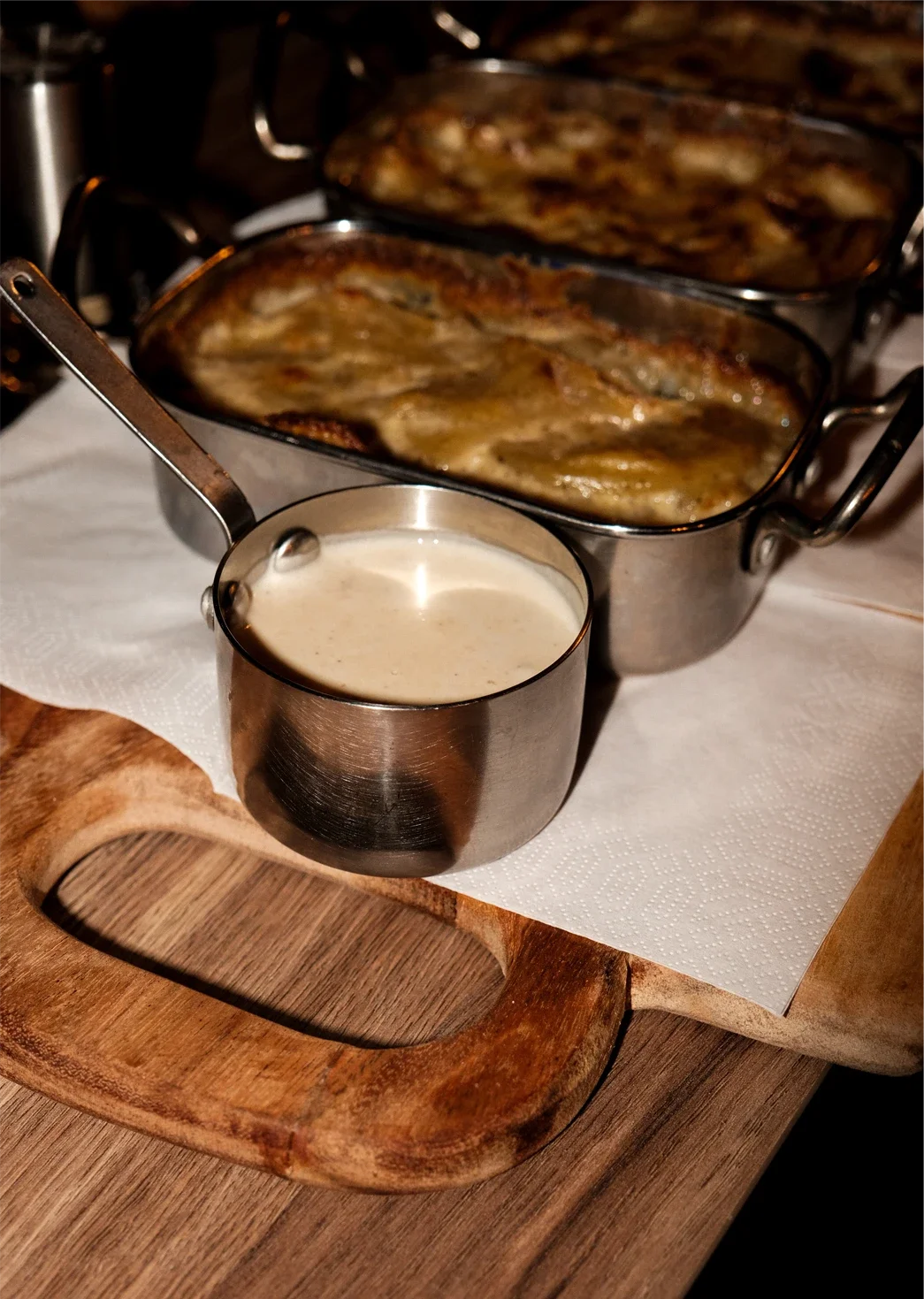 Plat de gratin de pommes de terre avec une sauce et un verre de crème ou de sauce à côté.