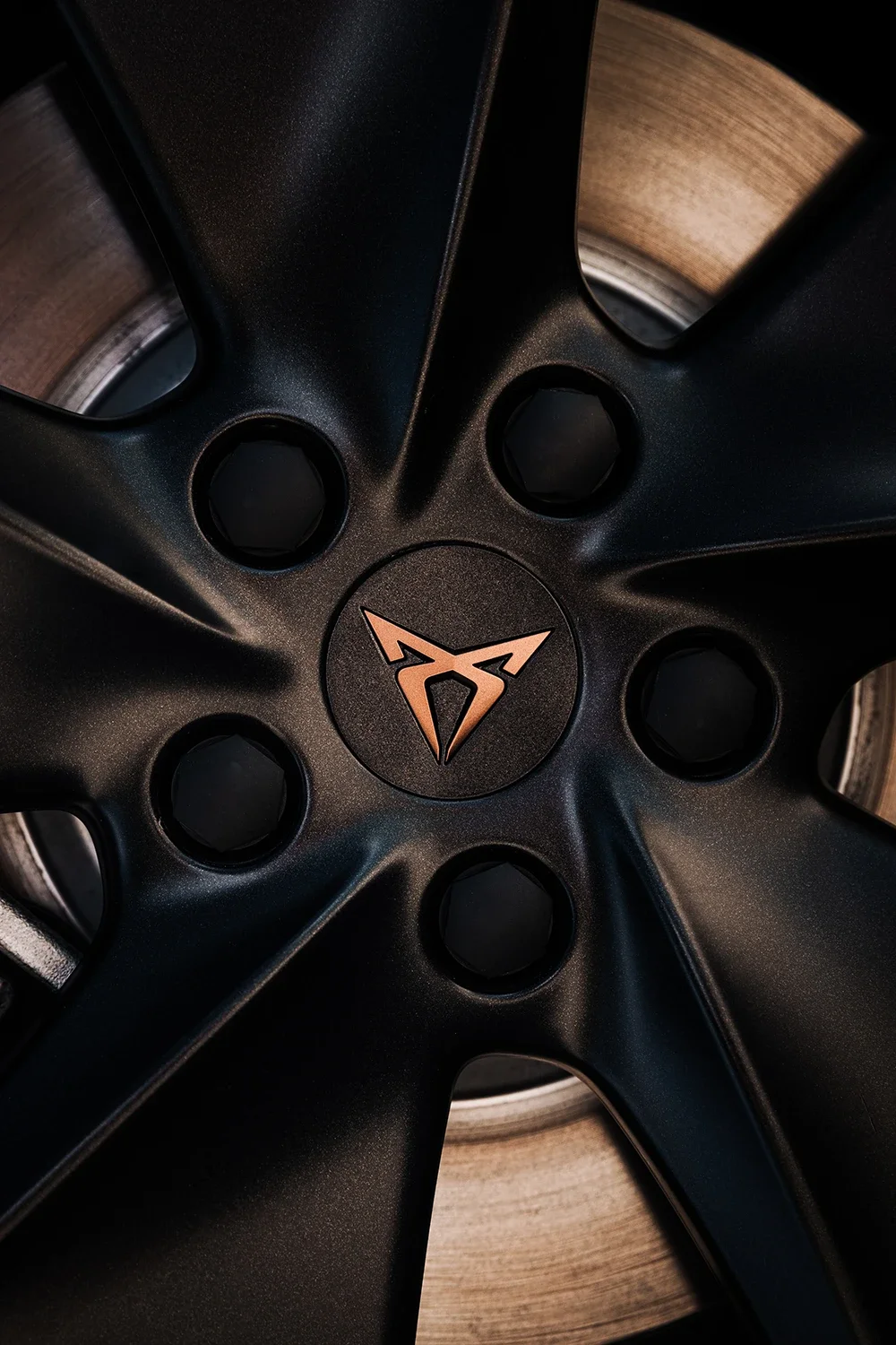 Vue d'un jante de voiture noire avec un logo au centre, posé sur un sol en bois.