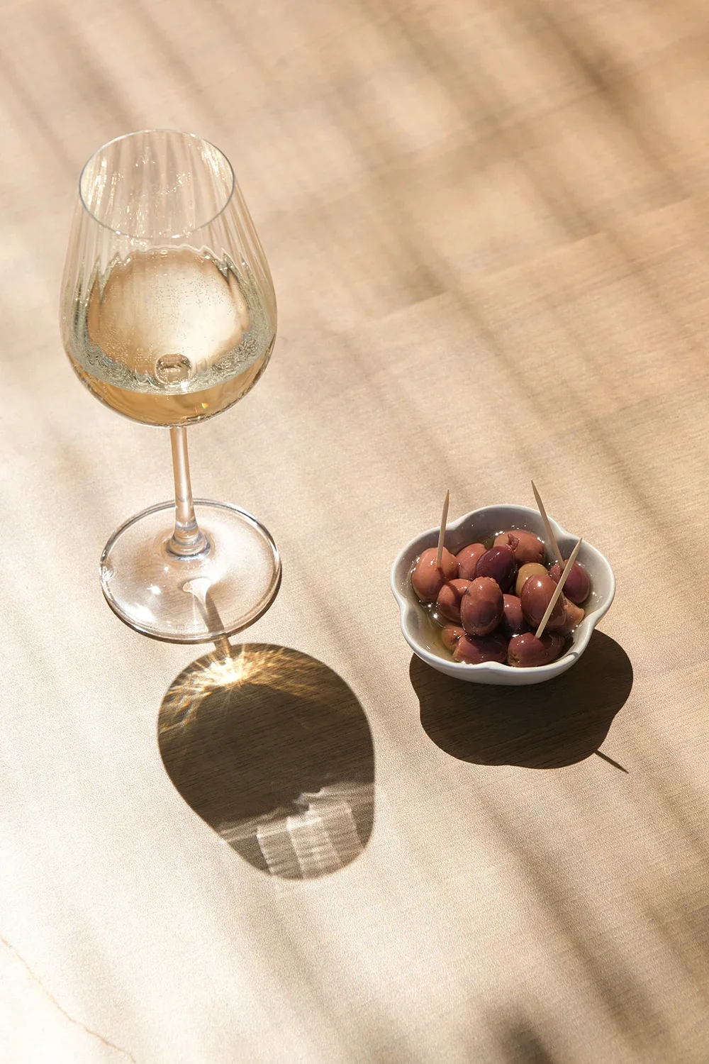 Verre de vin blanc à côté d'un bol contenant des olives avec des cure-dents
