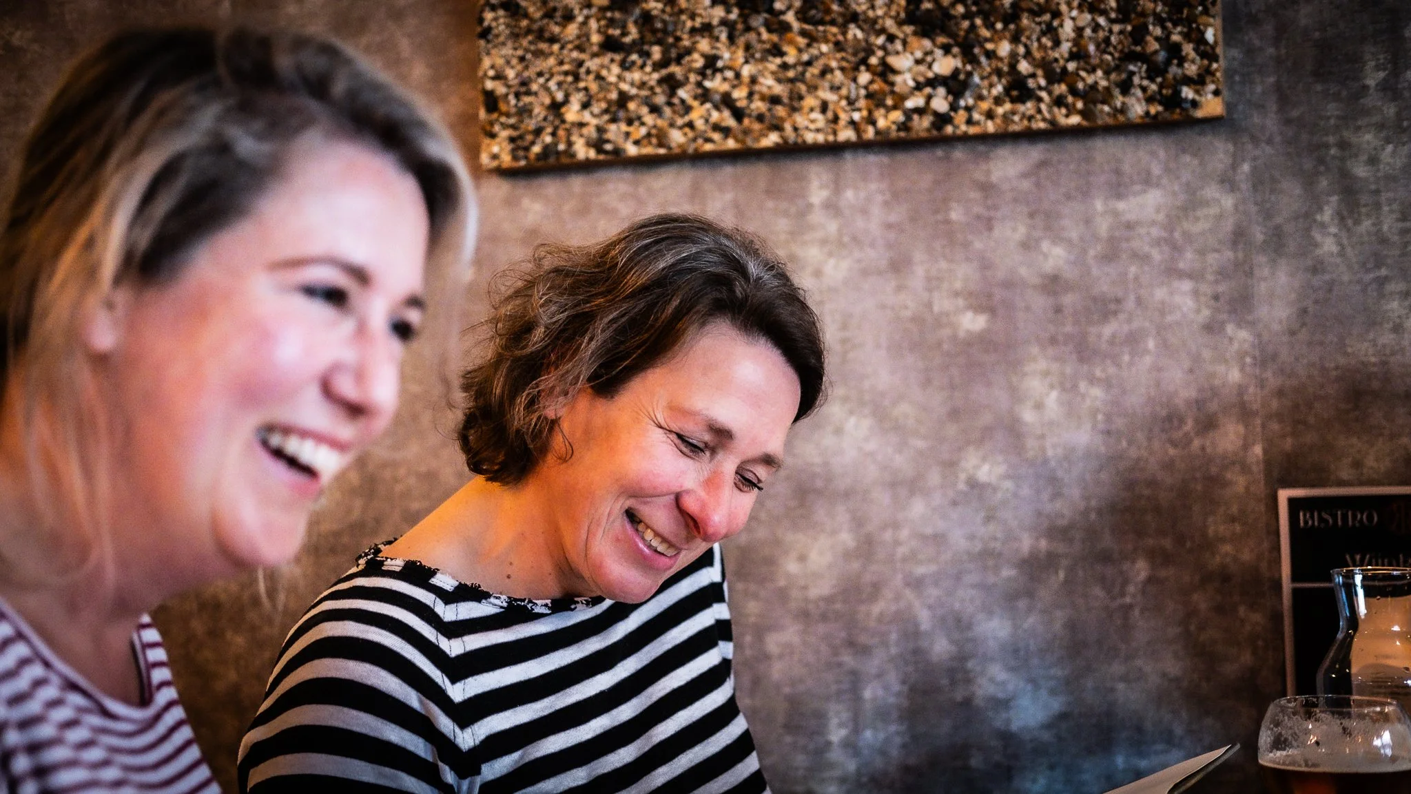 Two women laughing together at a restaurant table.