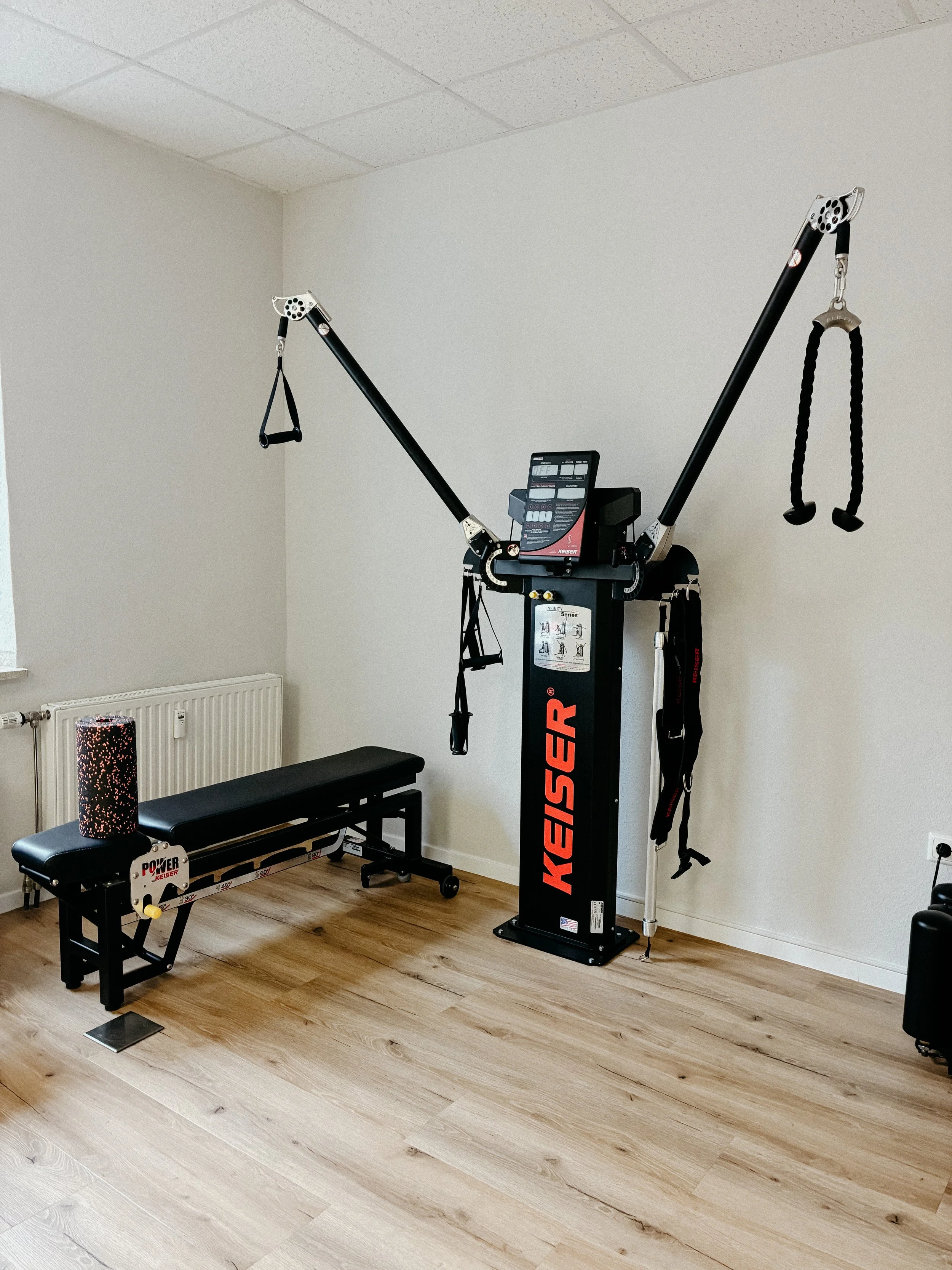 Ein Heimtrainingsgerät in einem Raum mit Holzfußboden und weißen Wänden.