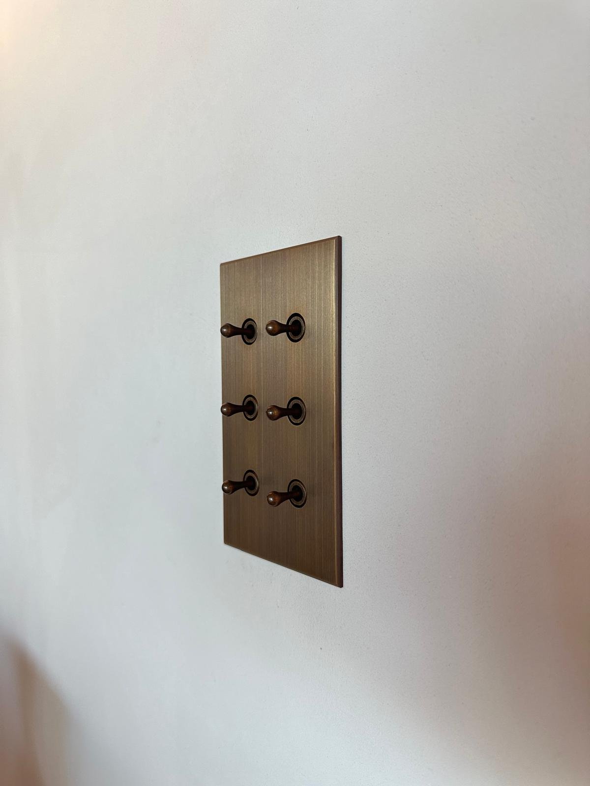 Interrupteur à levier en bronze sur un mur blanc.