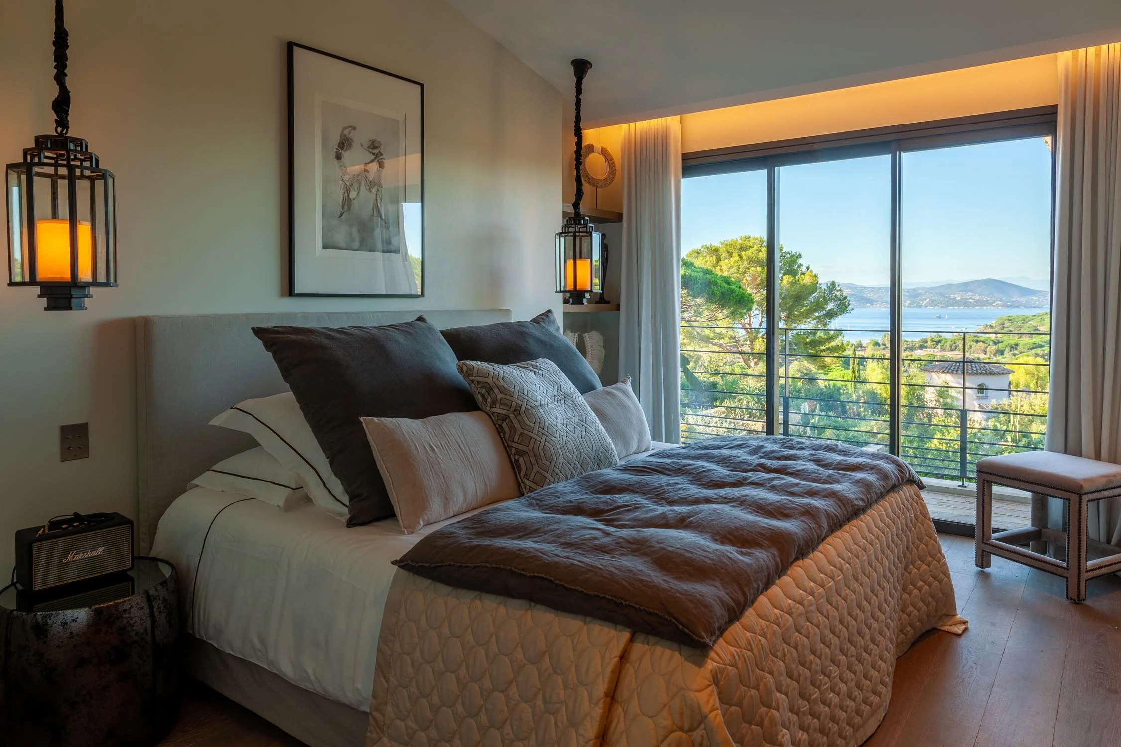 Chambre spacieuse avec lit à baldaquin, grands coussins, vue sur la mer et la nature à travers de grandes fenêtres.