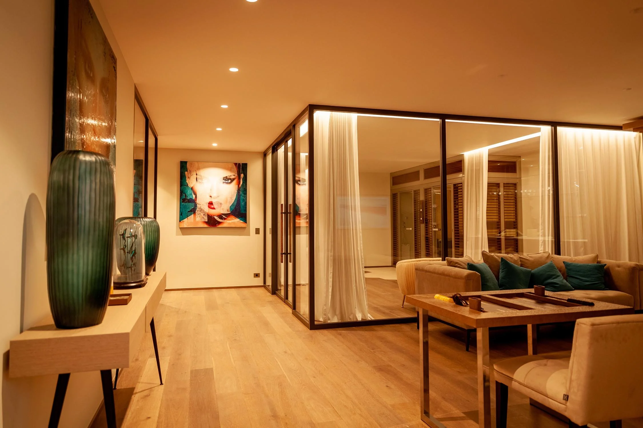 Intérieur moderne d'un salon avec canapé beige, coussins turquoise, table en bois, grandes fenêtres avec rideaux blancs, tableaux colorés, décoration avec vases verts