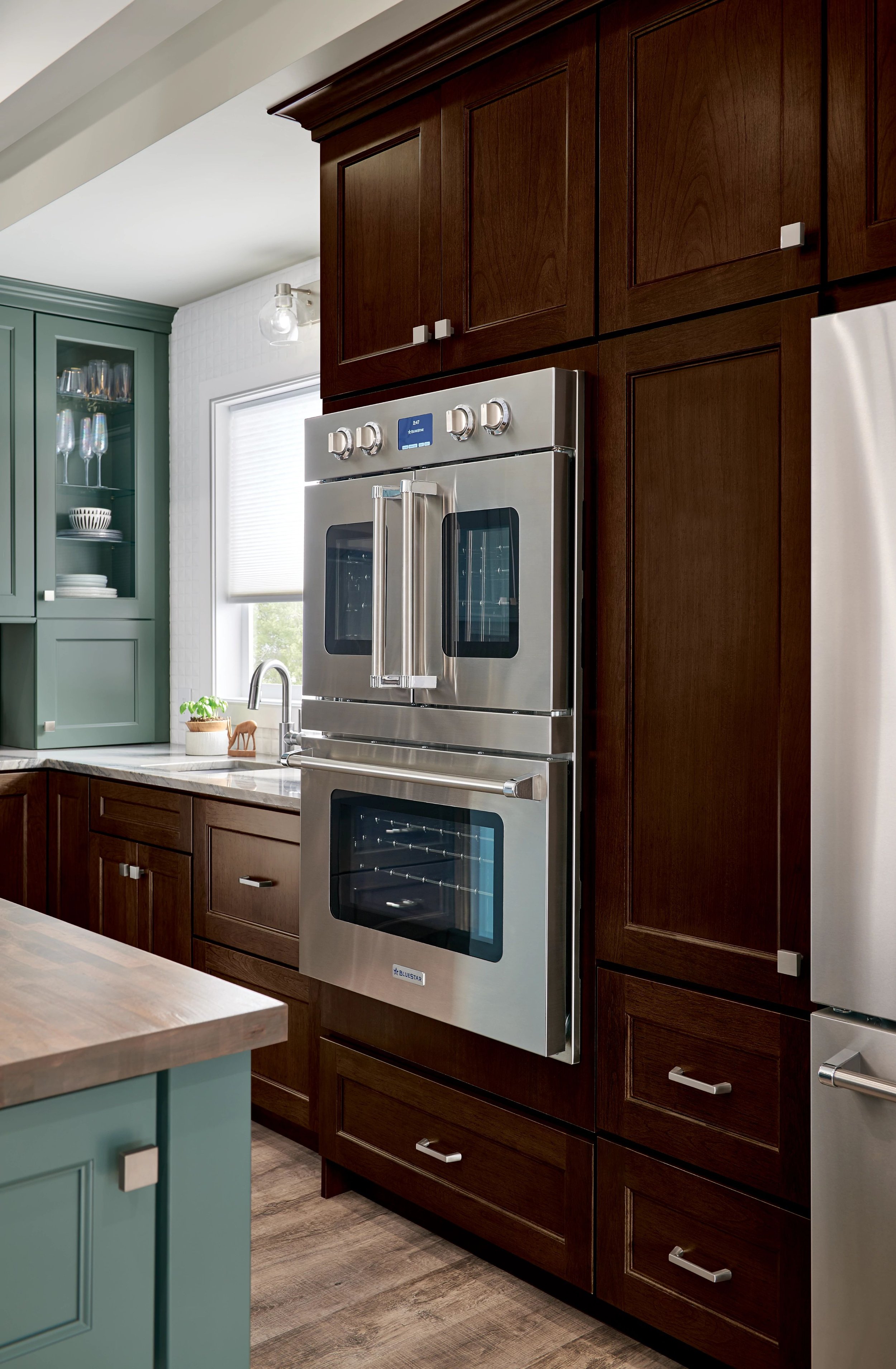 Modern kitchen with dark wood cabinets, a stainless steel oven, and a green cabinet near the window.