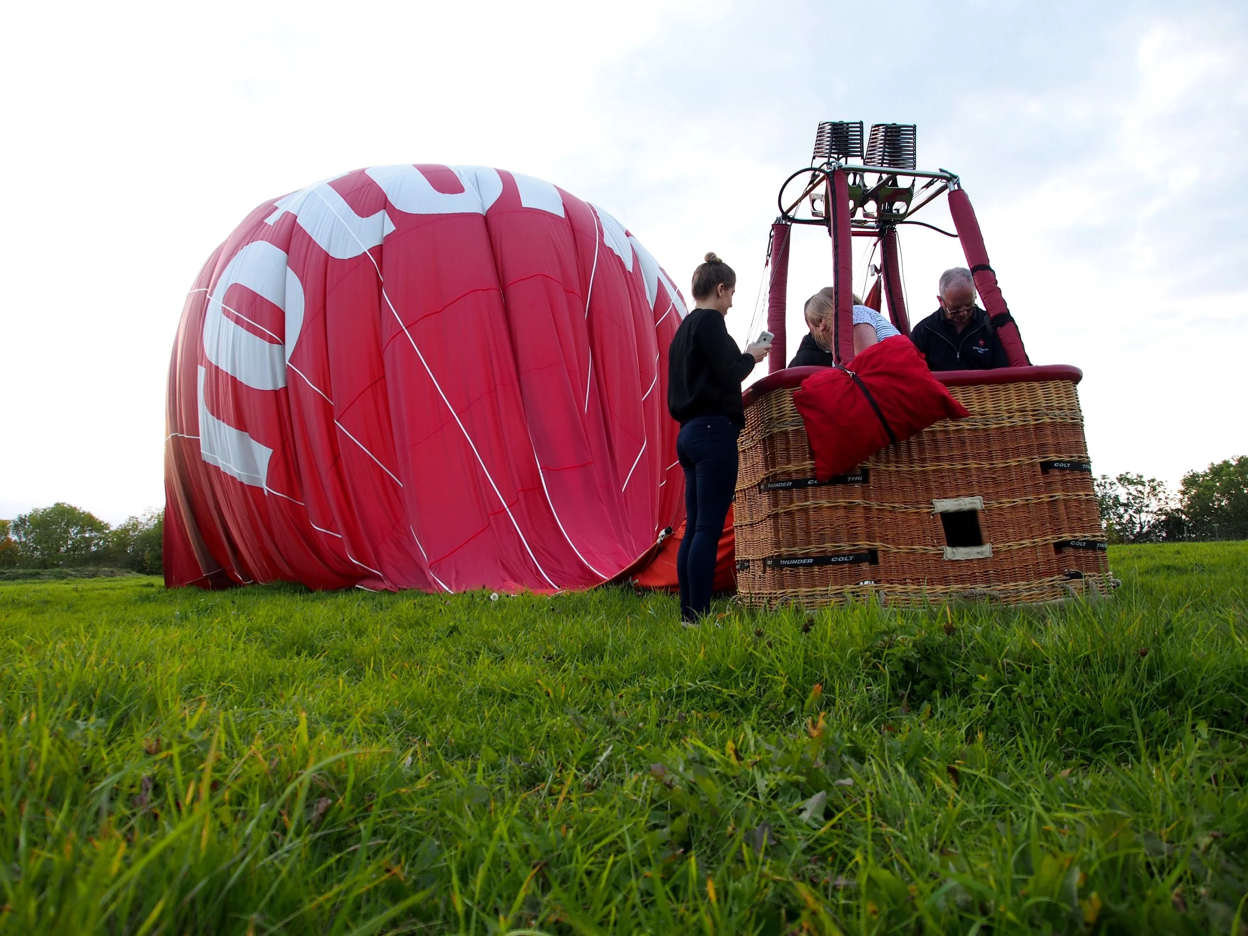 A hot air balloon sitting on the grass, with people inside the basket