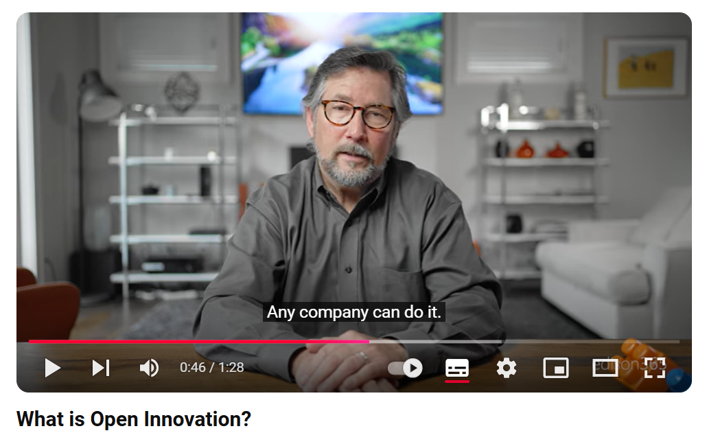 A man wearing a grey shirt presents from a living room. The closed captions on the screen say, "any company can do it".