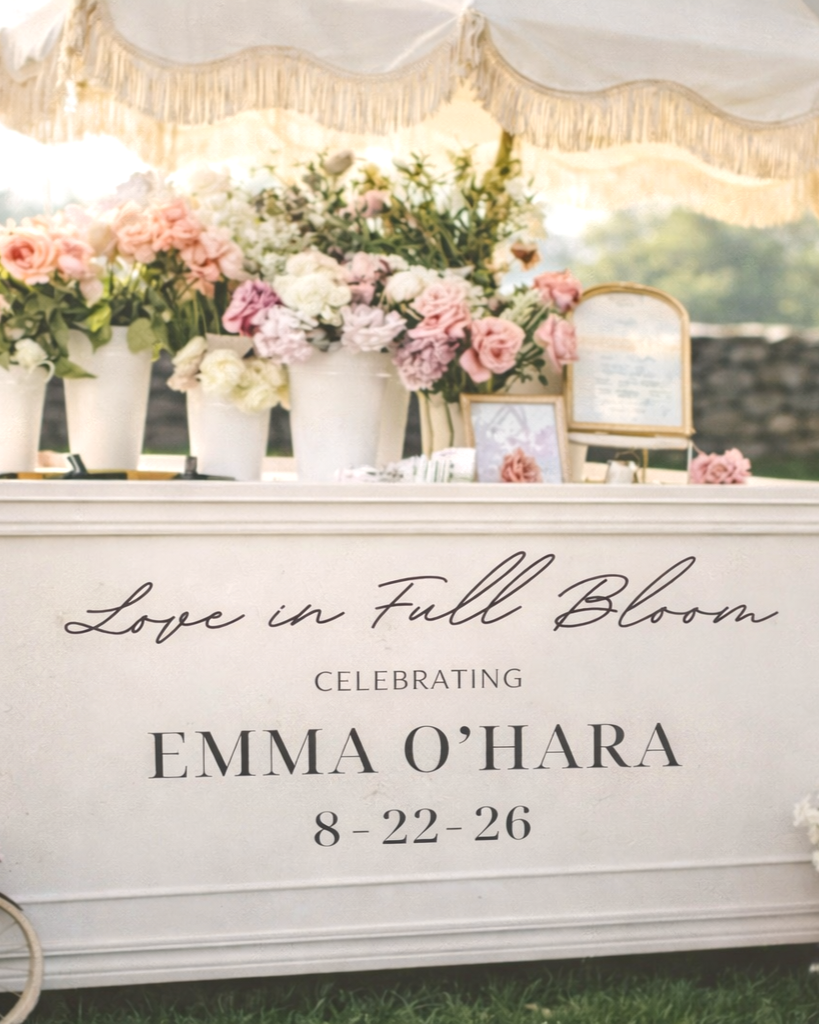 A white floral display with pink and white flowers in vases and a table for a celebration honoring Emma O'Hara, with the date August 22-26.