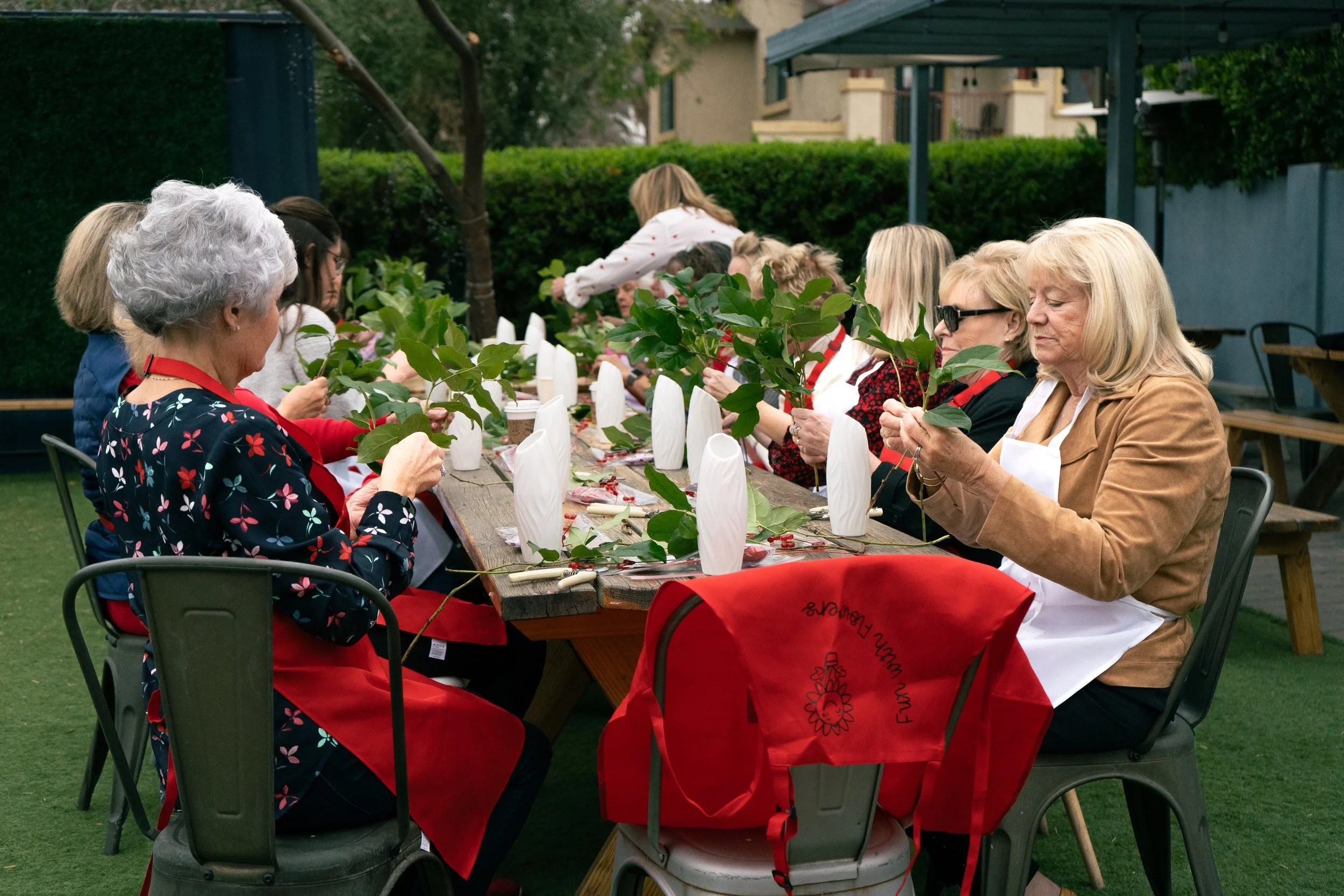 Guests gathered around a table for a floral arranging workshop at a Sarasota event.