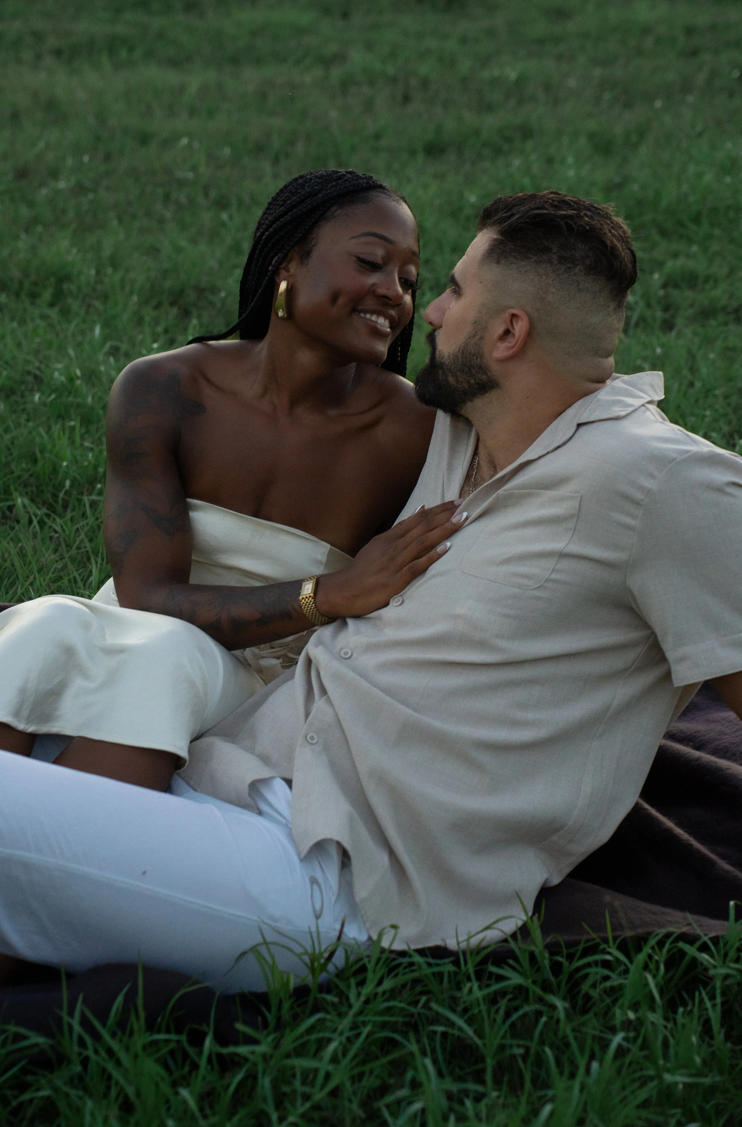 Couple sitting together in a grassy outdoor setting during a romantic couples portrait session in Sarasota, Florida.
