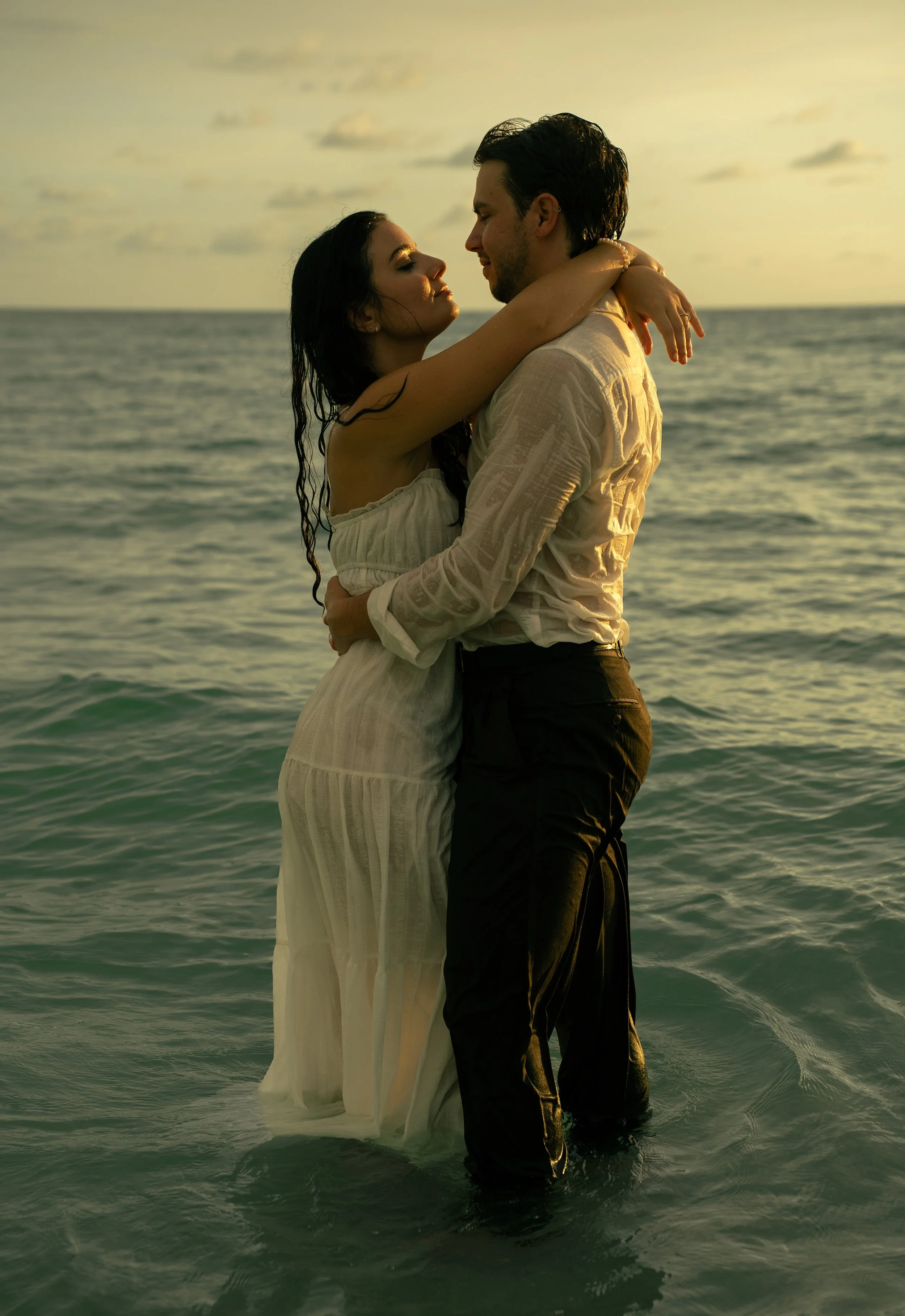 Couple embracing in the ocean at sunset during a romantic Lido Beach photography session in Sarasota, Florida.