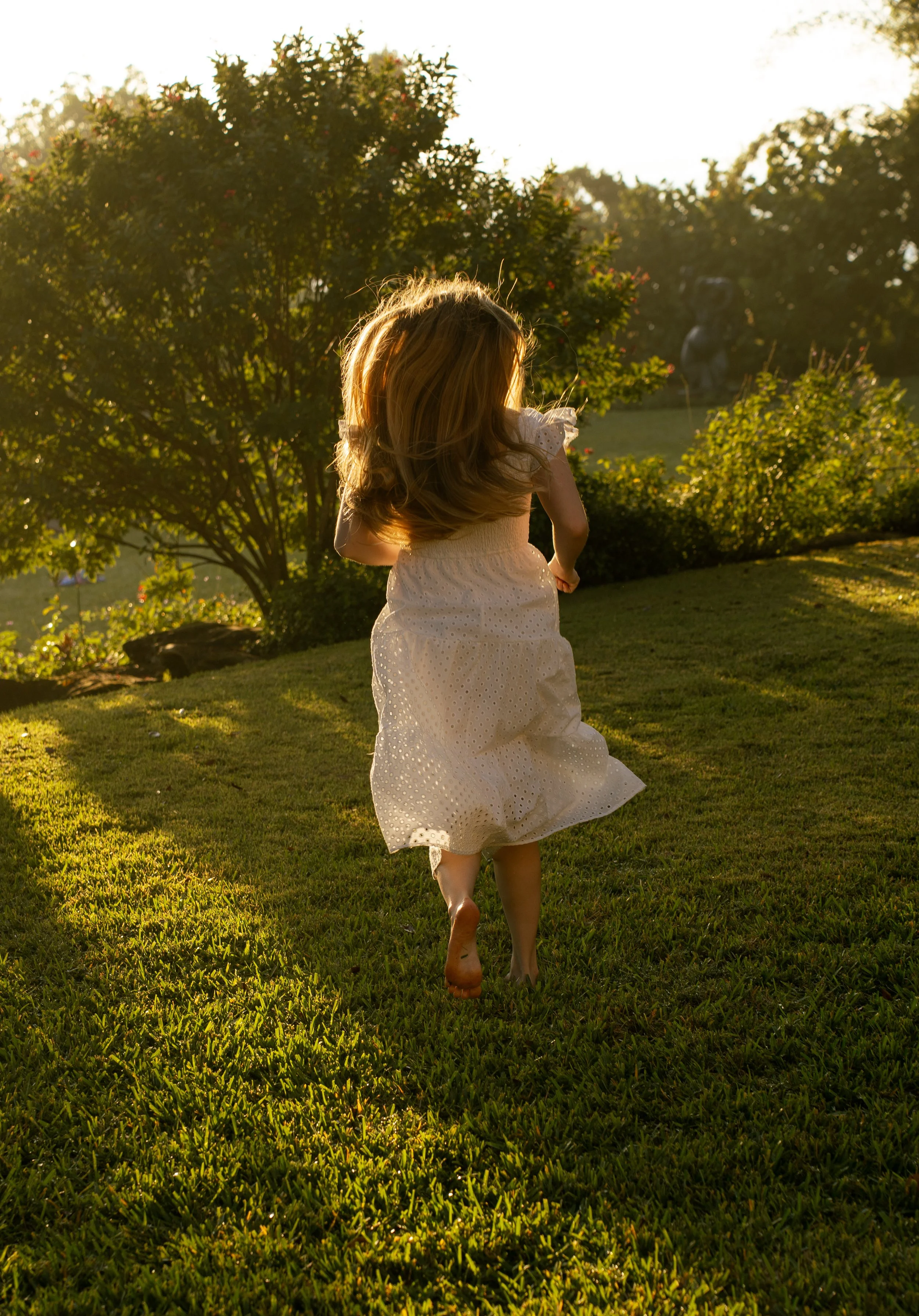 Woman walking through a sunlit backyard during an outdoor portrait session in Sarasota, Florida