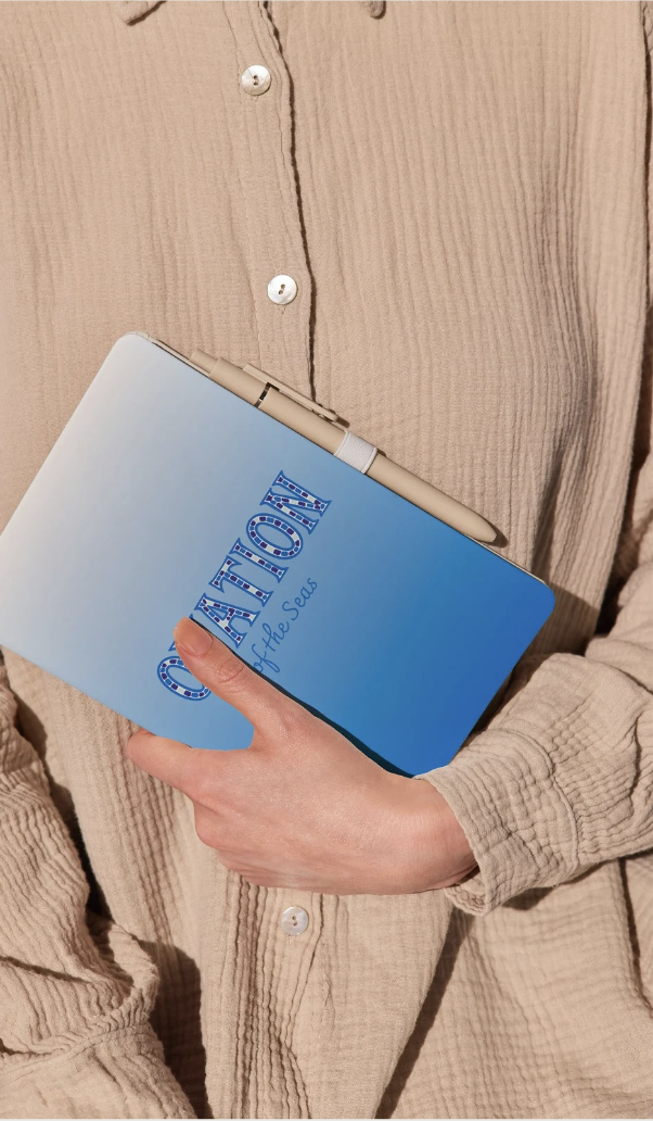 Person holding a blue book titled 'ADVOCACY of the Seas' with a pen in hand, wearing a beige textured button-up shirt.